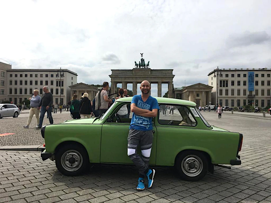 Björn „Paolo“ Petersen vor seinem grünen Trabant am Brandenburger Tor in Berlin.