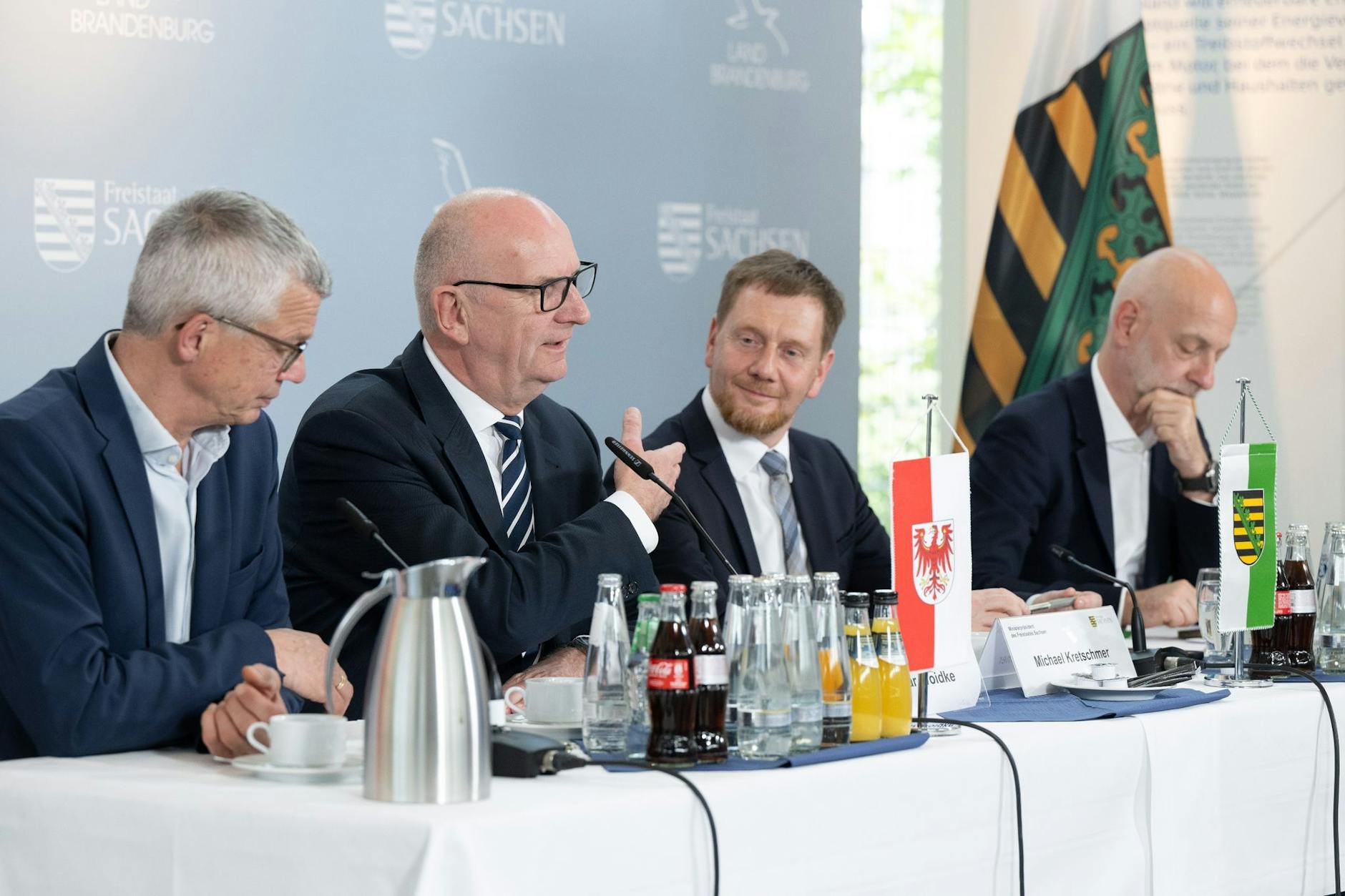 Florian Engels (l-r), Regierungssprecher, Dietmar Woidke (SPD), Ministerpräsident von Brandenburg, Michael Kretschmer (CDU), Ministerpräsident von Sachsen, und Ralph Schreiber, Regierungssprecher, nehmen nach einer bilateralen Kabinettssitzung im Kraftwerk Boxberg an einer Pressekonferenz teil.