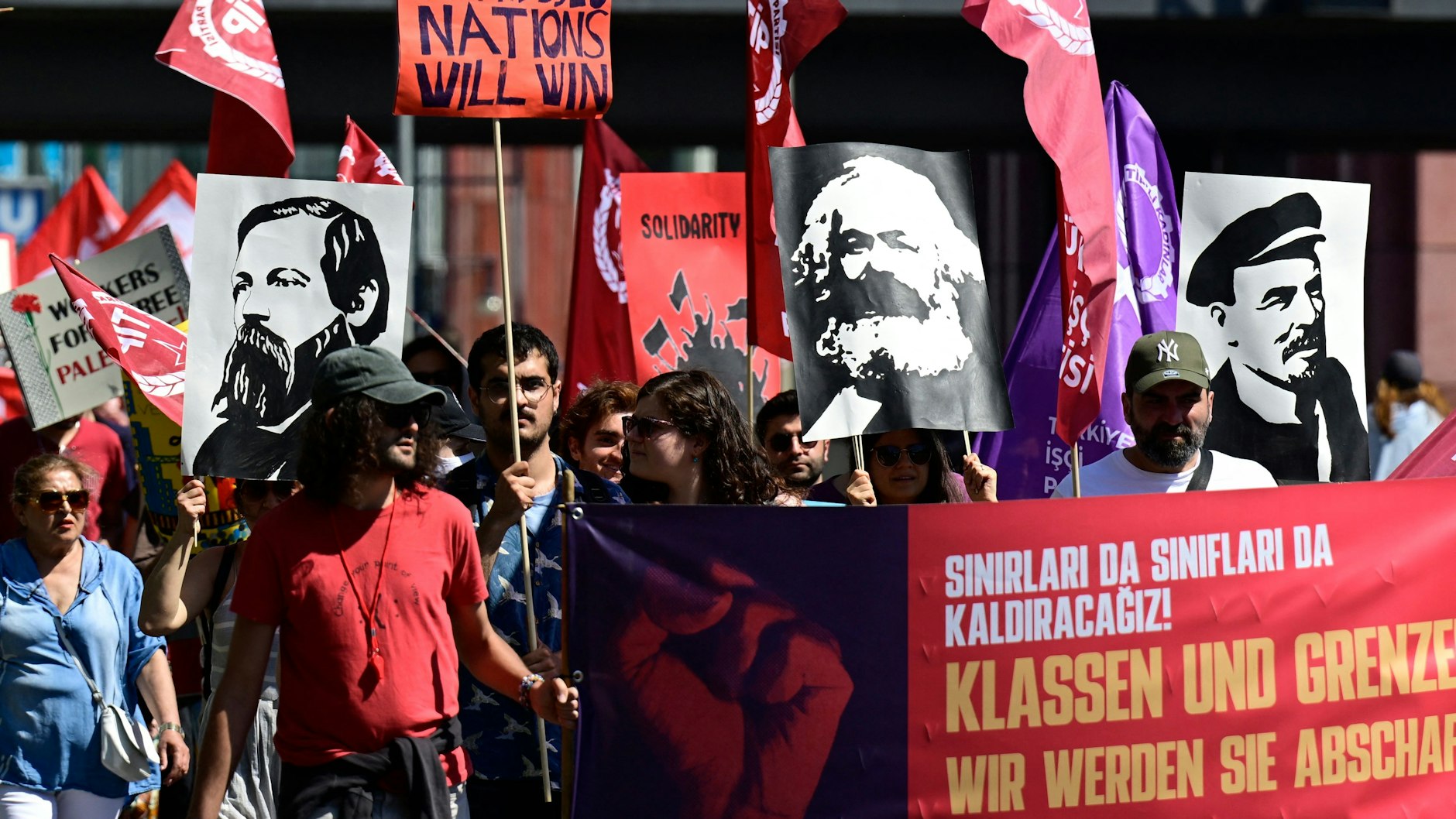 In der DGB-Demo zeigen Teilnehmer die Bilder der einstigen kommunistischen Führer Karl Marx, Friedrich Engels und Wladimir Iljitsch Lenin.