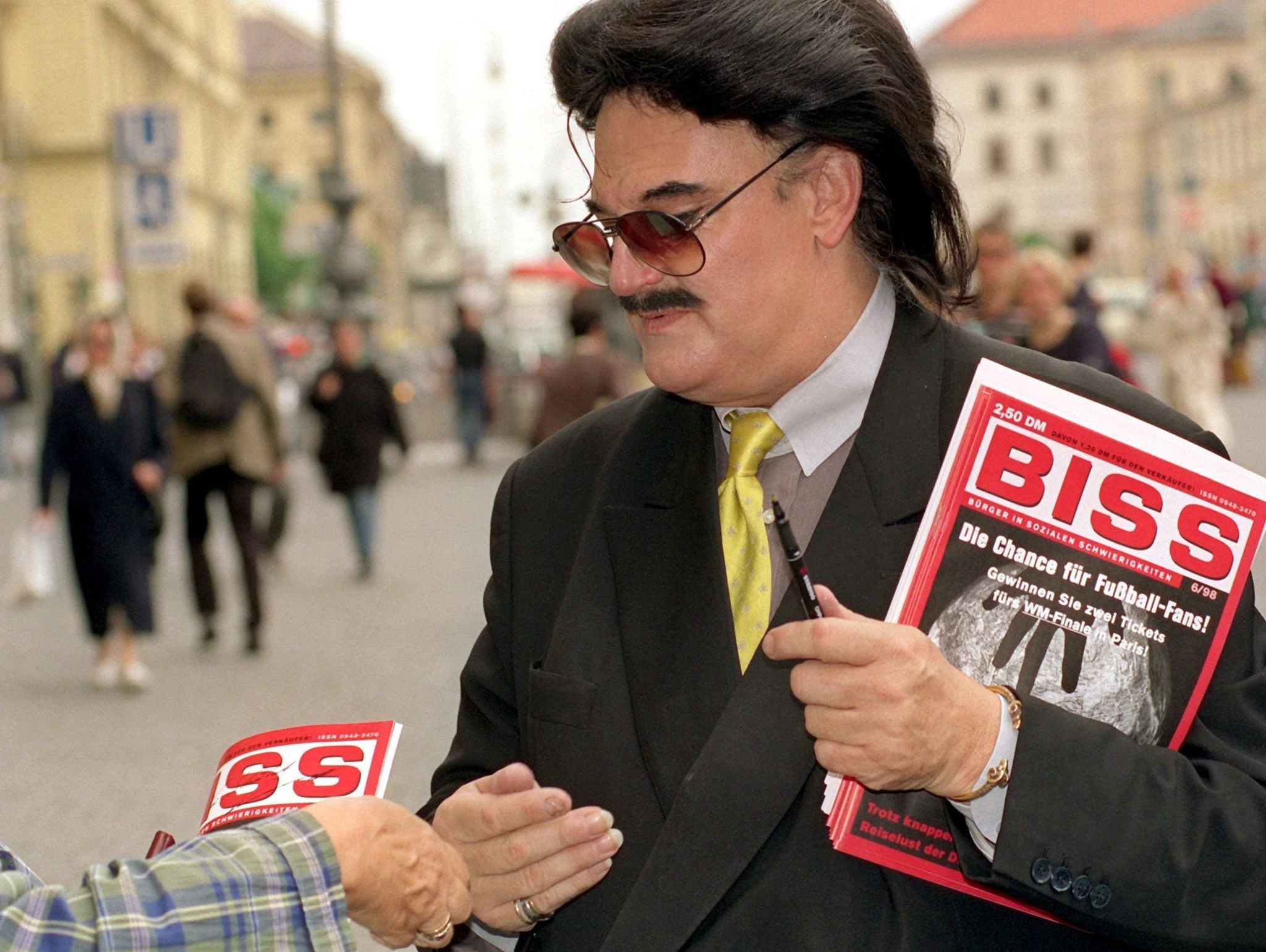 ARCHIV - Rudolph Moshammer verkauft auf dem Odeonsplatz das Straßenmagazin «Biss». Jenseits des Rummels kümmerte sich der Modezar um Obdachlose.  
