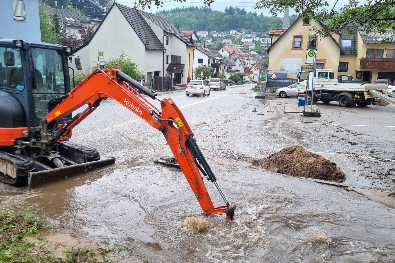 Schriesheim: Mit einem kleinen Bagger wird versucht, den Bestbach freizuschaufeln, um das Wasser von der überfluteten Straße abfließen zu lassen.