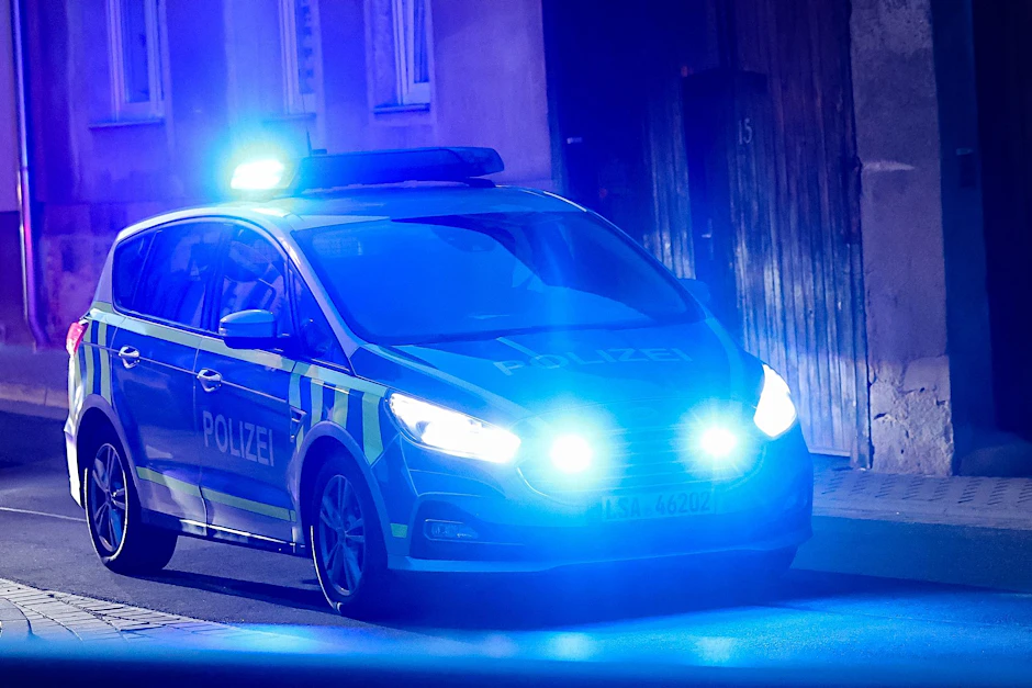 ARCHIV - Ein Fahrzeug der Polizei fährt mit Blaulicht am Abend durch eine enge Straße.  