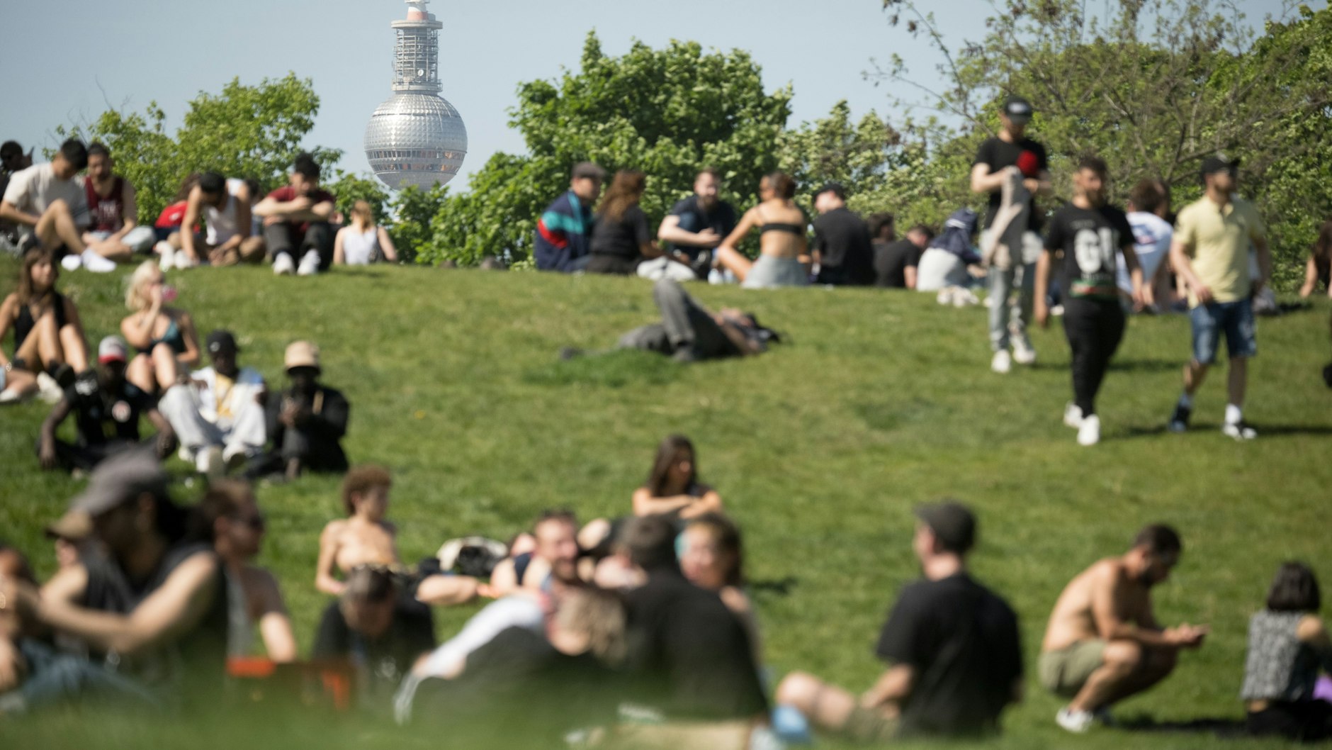 Menschen sitzen am 1. Mai bei Sonnenschein im Görlitzer Park.