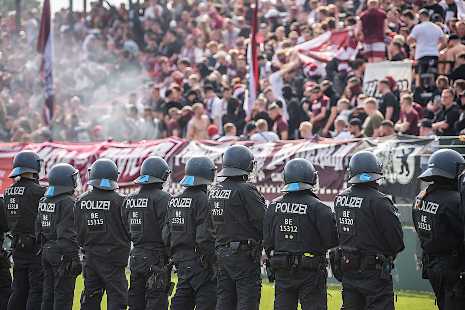 Das Spiel wird wegen mangelnder Sicherheit unterbrochen und die Polizei betritt das Spielfeld.