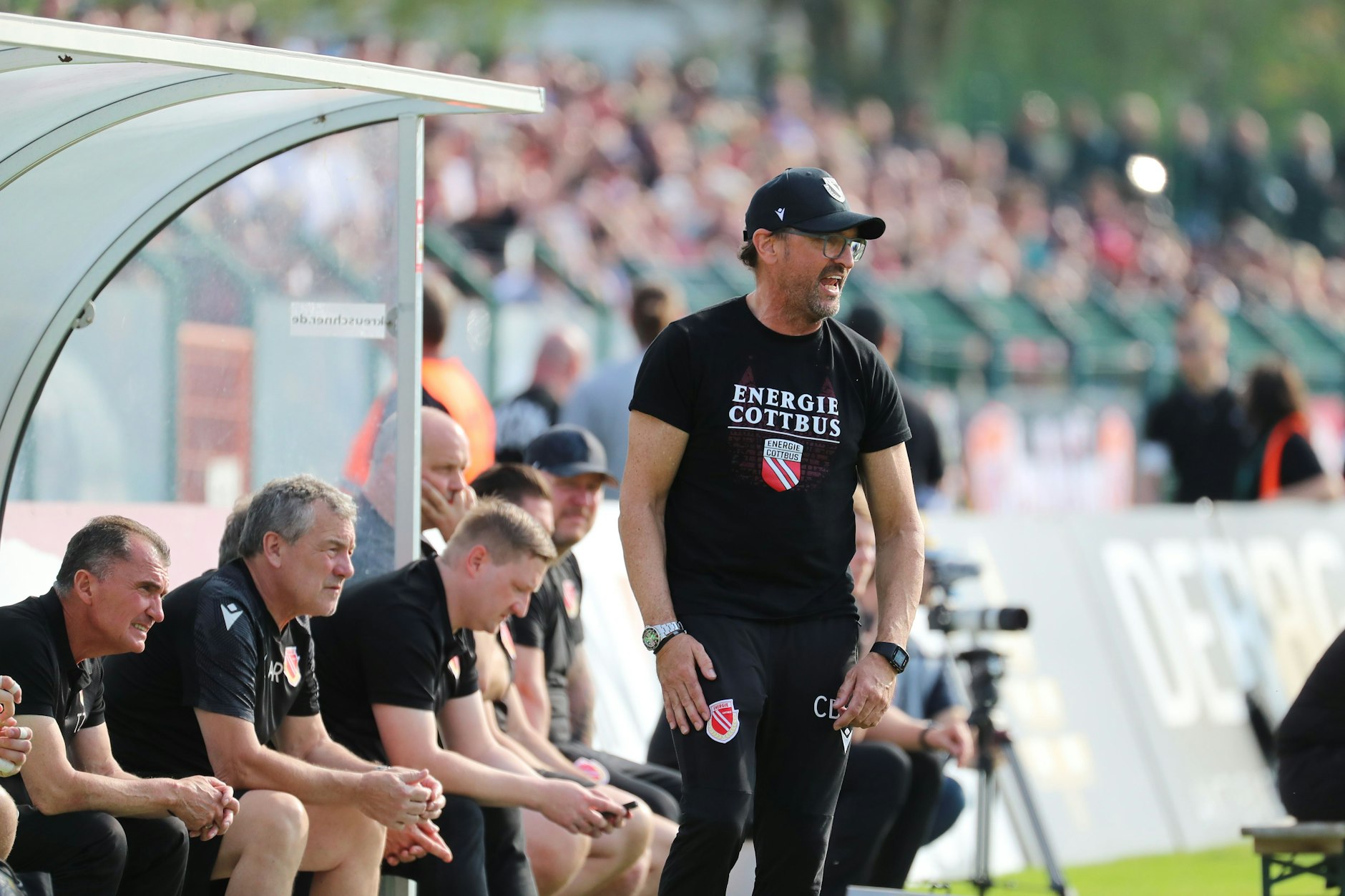 Claus-Dieter Wollitz im schwarzen Dress mit Basecap. Nicht immer sah der Auftritt des Cottbus-Trainers beim BFC so friedlich aus.