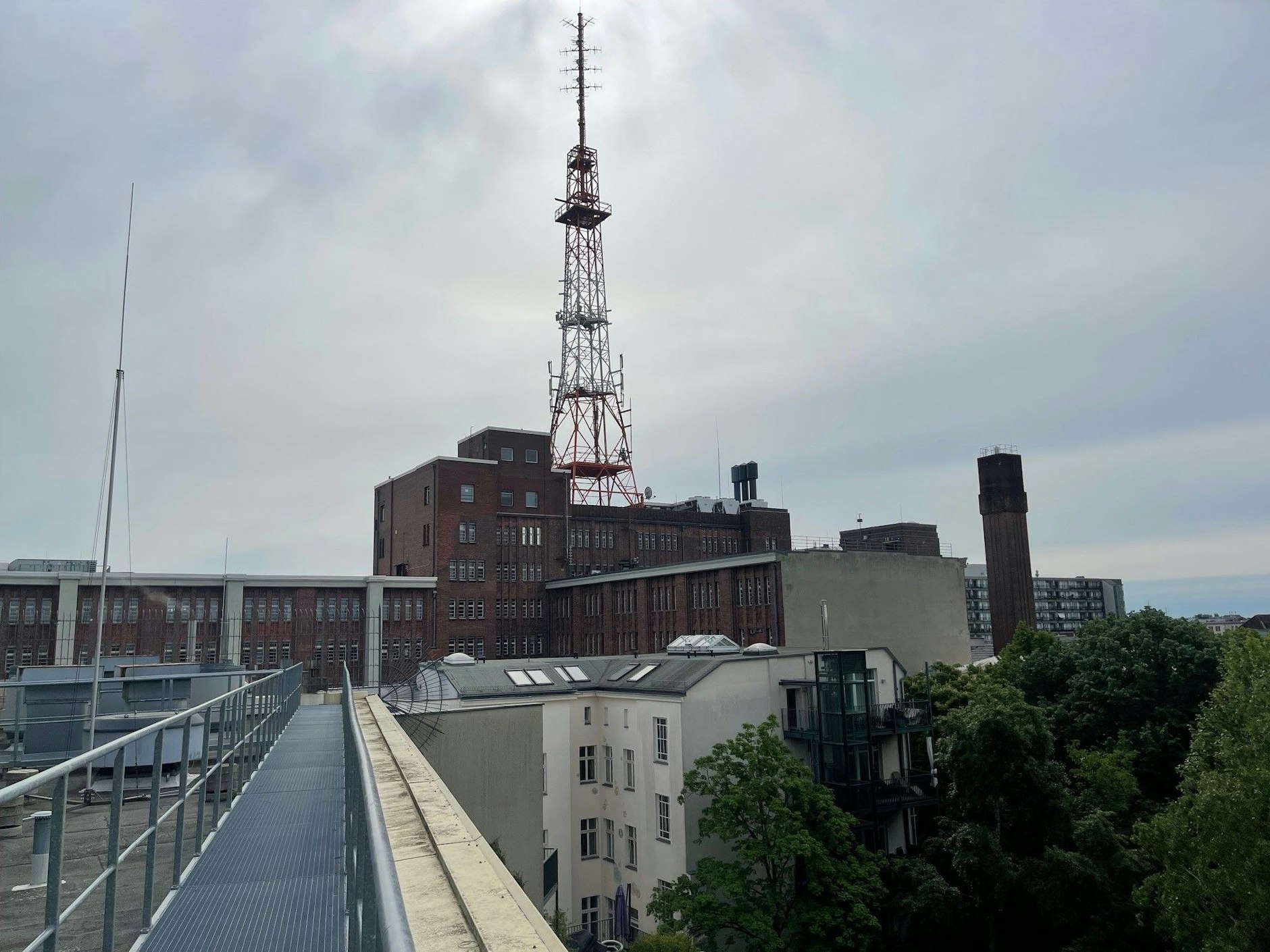 Ein Funkturm auf dem Dach der Telekom. Im Hintergrund – hinter dem Schornstein – der Wohnkomplex Pallasseum. 140 Meter müssen unterirdisch überbrückt werden.