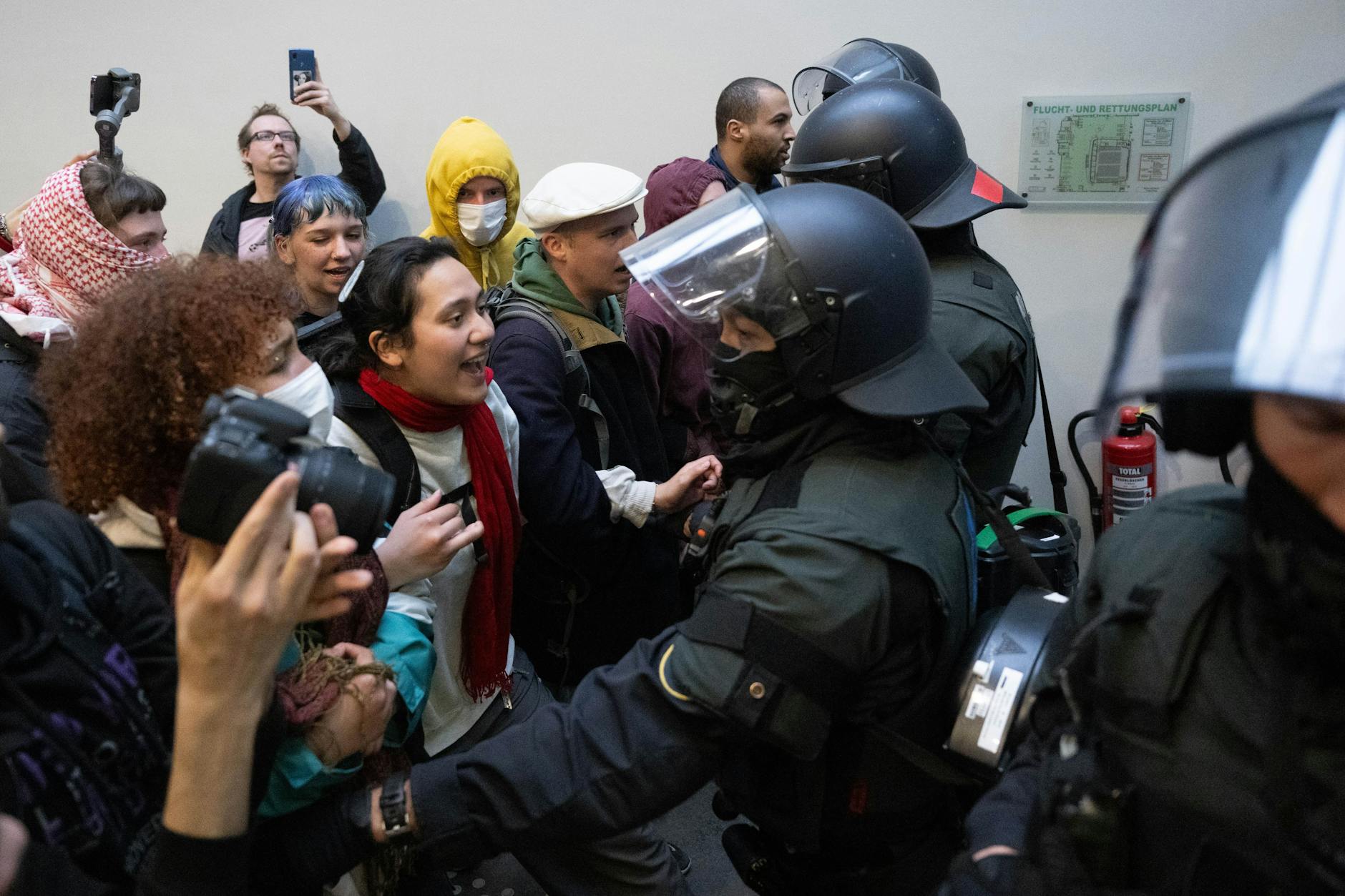 Polizisten stehen vor dem besetzten Audimax der Universität Leipzig protestierenden Menschen gegenüber.