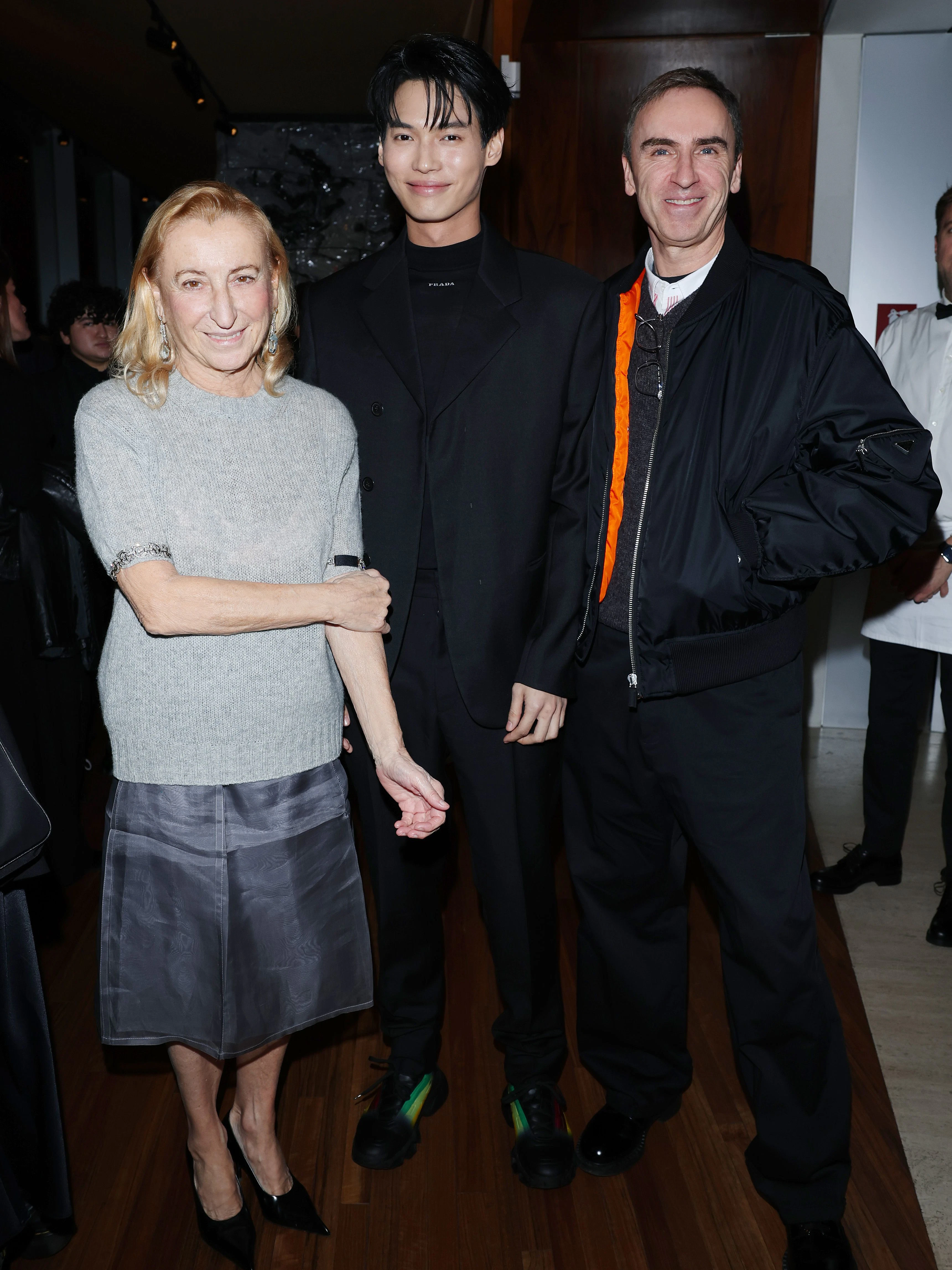 Mailand, Januar 2023: Miuccia Prada und Raf Simons mit dem Schauspieler Metawin Opas-iamkajorn im Ristorante Torre auf dem Gelände der Fondazione Prada. Man beachte ihren knielangen Rock mit den aufgedruckten Knickfalten.