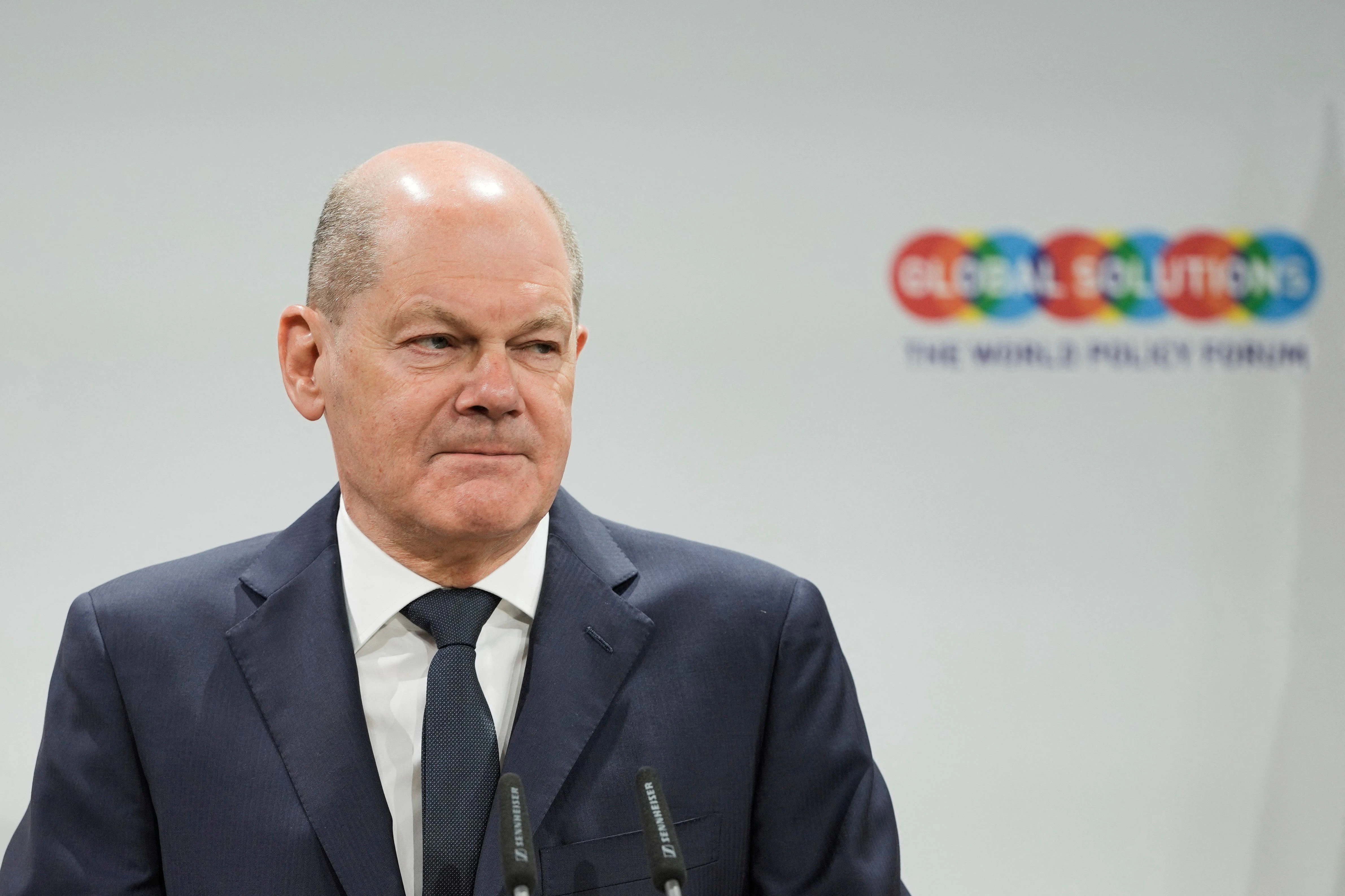 Wollen wir mal davon ausgehen, dass <strong>Olaf Scholz</strong> am Dienstagmorgen völlig arglos in seinen Schrank gegriffen, von 20 Anzügen den erstbesten herausgenommen und sich bei vier Handvoll Exemplaren, die mehr oder minder identisch aussehen, kaum Gedanken gemacht hat, welche nachtblaue Hosen-Sakko-Kombi nun besonders gut zum Global Solutions Summit passt. Dass sein Jäckchen nicht sonderlich gut sitzt und im Schulterbereich wie an den Armen unschön beult? Sei’s drum! Wir finden unter dem Gesichtspunkt der vestimentären Symbolik eher die Kragenverarbeitung fraglich: Zu einer Konferenz, bei der es um die ganz großen geopolitischen Zusammenhänge und mithin auch um Deutschlands Stand in der Welt geht, ausgerechnet ein fallendes Revers? Ein Schelm, wer Böses dabei denkt! Ein enthusiastisch und kraftvoll in die Höhe gerecktes steigendes Revers hätte womöglich ein schöneres Zeichen gesetzt, wenn auch ein ganz kleines …