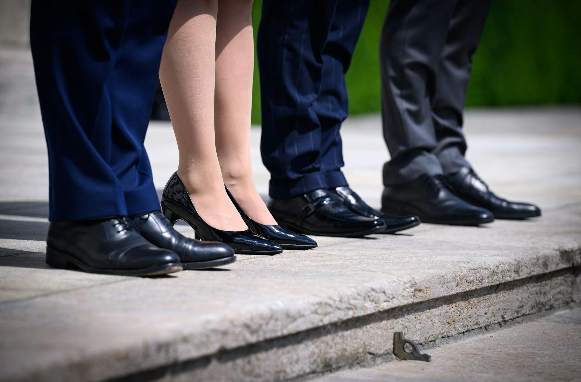 ARCHIV - Eine Frau steht zwischen drei Männern in Anzügen auf den Treppenstufen von Schloss Bellevue.