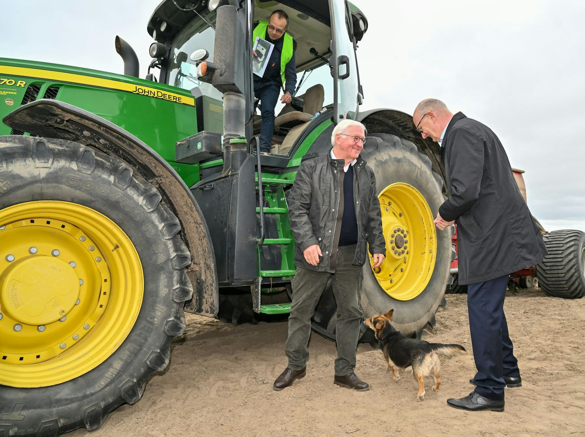 Bundespräsident Frank-Walter Steinmeier (M) und Dietmar Woidke (r, SPD), Ministerpräsident von Brandenburg, stehen bei Benjamin Meise, Landwirt eines Agrarbetriebs, auf einem Acker.  