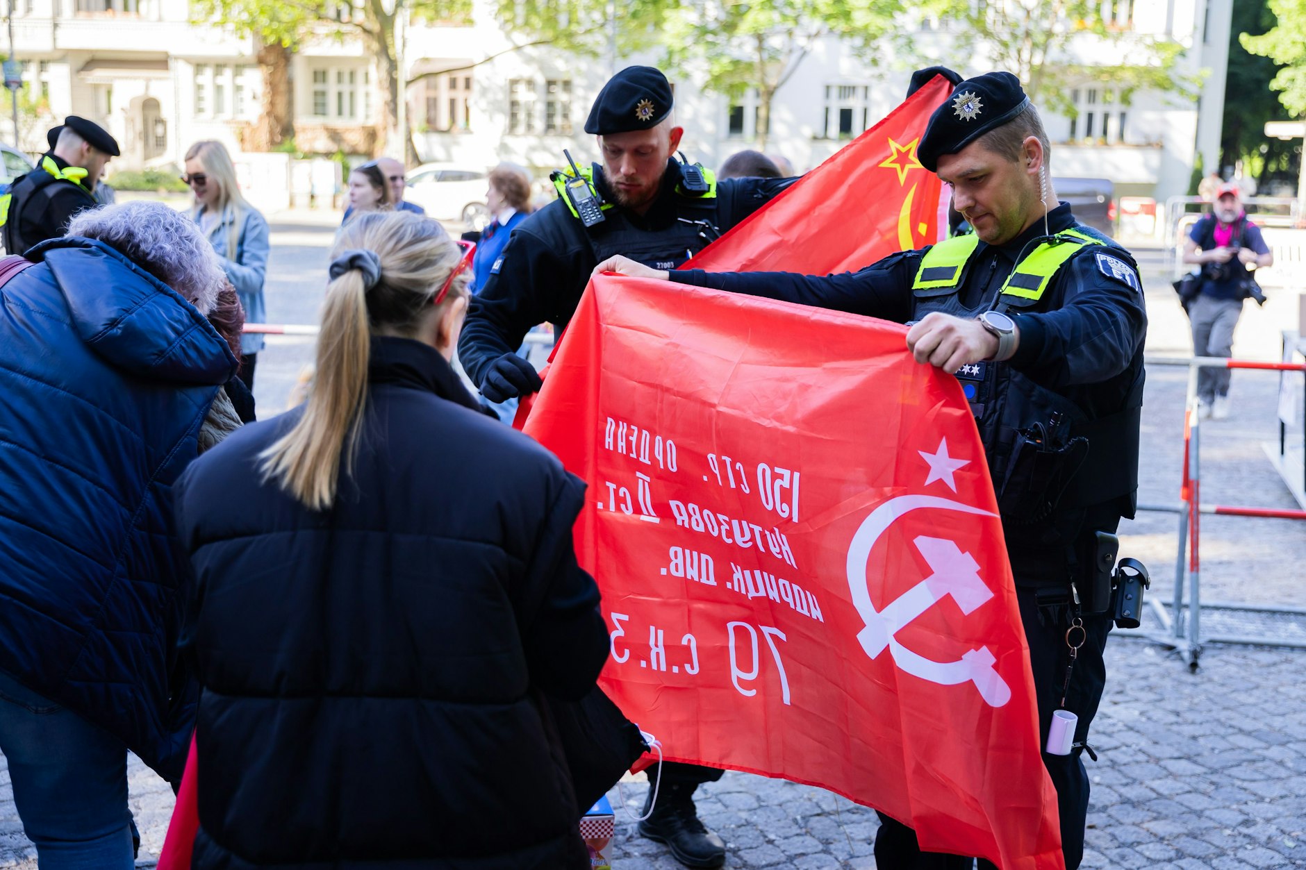 Polizisten überprüfen am Eingang des Sowjetischen Ehrenmals im Treptower Park Besucherfahnen auf verbotene Symbole.