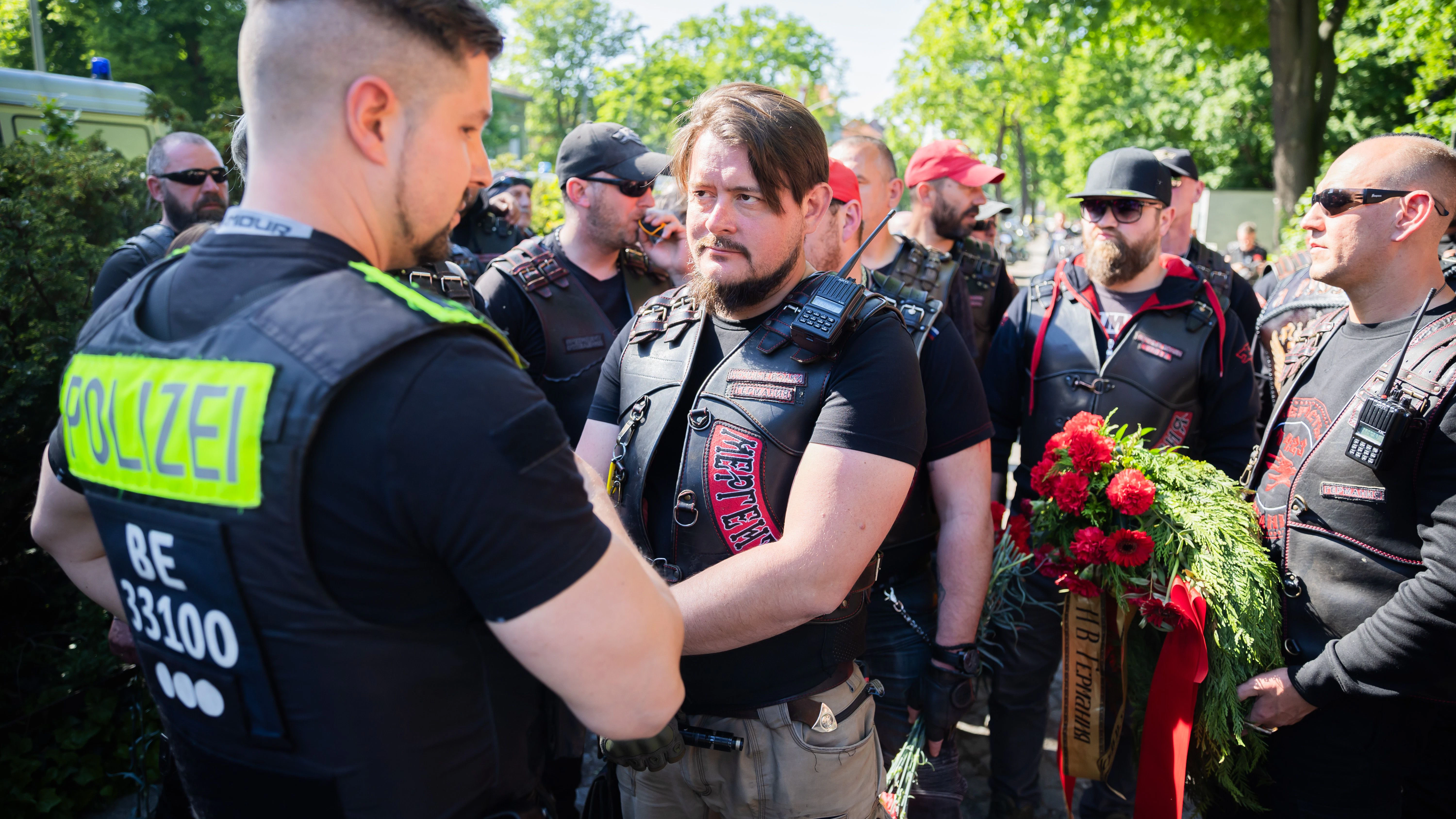 Ein Mitglied der russisch-nationalistischen Rockergruppe "Nachtwölfe" spricht vor dem Ehrenmal im Treptower Park mit einem Polizisten.