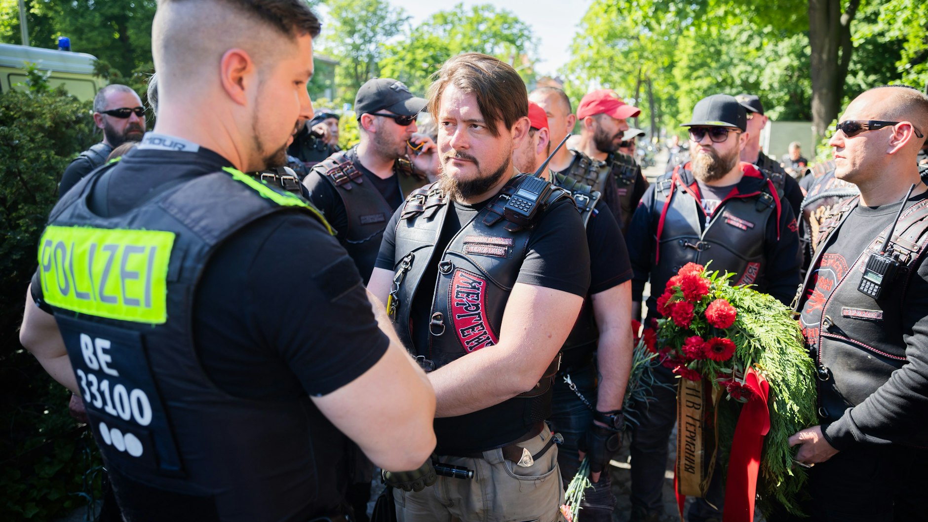 Ein Mitglied der russisch-nationalistischen Rockergruppe "Nachtwölfe" spricht vor dem Ehrenmal im Treptower Park mit einem Polizisten.