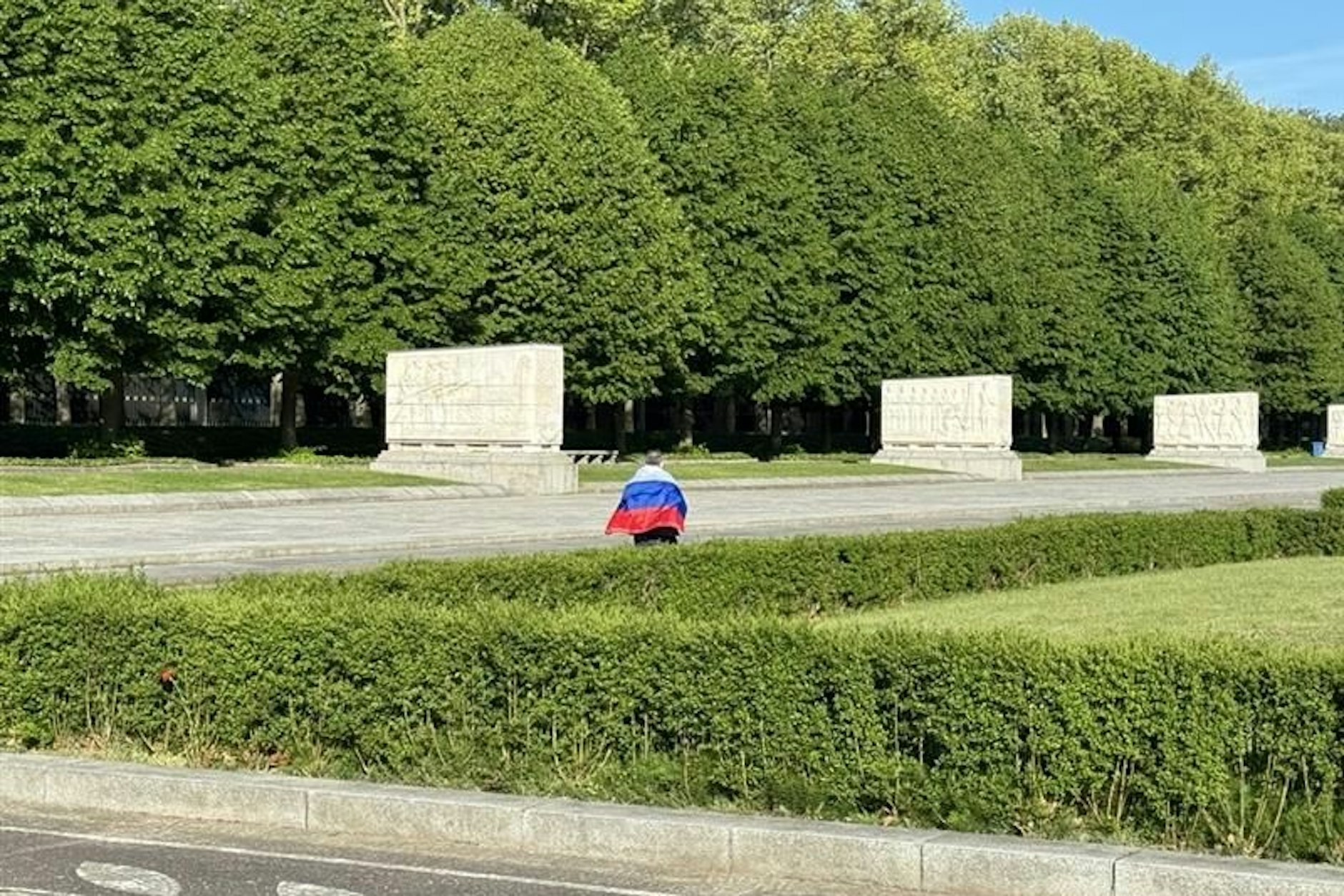 Ein Mann mit einer russischen Flagge auf den Schultern geht durch den Treptower Park in Berlin.