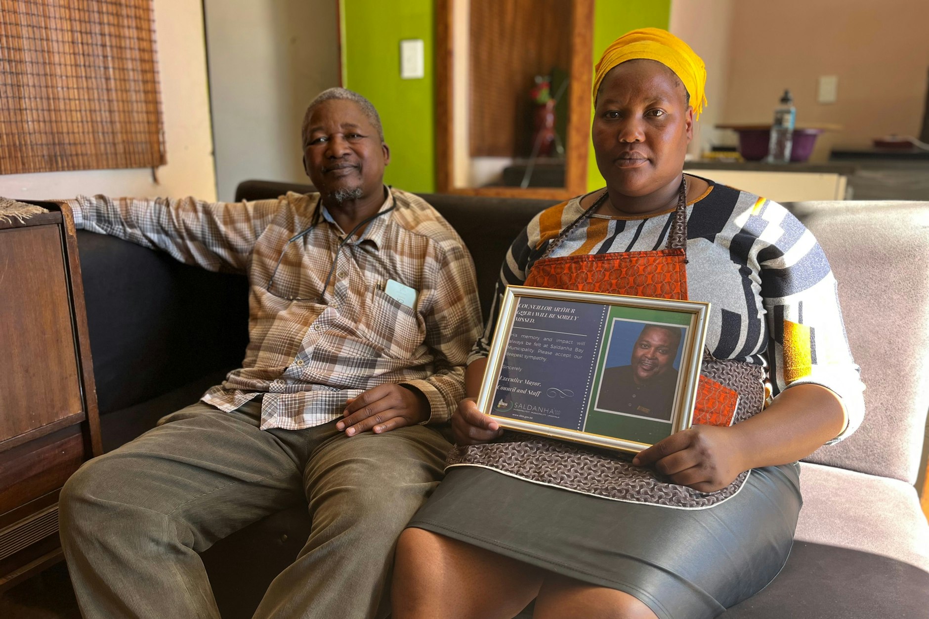 Arthur Gqebas Witwe Ntombekhaya und sein Onkel Vivid Mgoqi mit einem gerahmten Foto des ermordeten Lokalpolitikers.