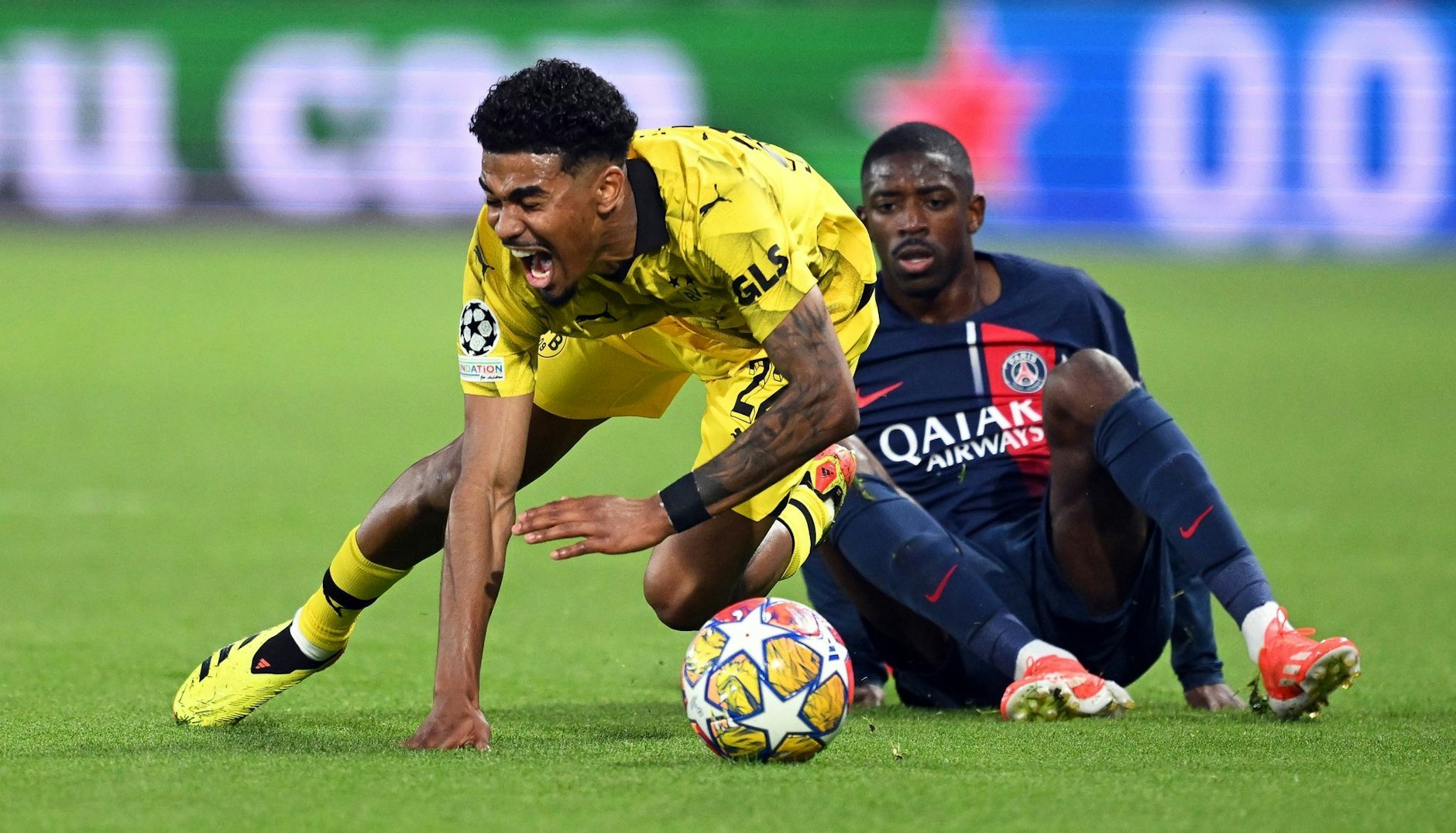 BVB-Verteidiger Ian Maatsen (l) wird von Ousmane Dembelé zu Fall gebracht.  