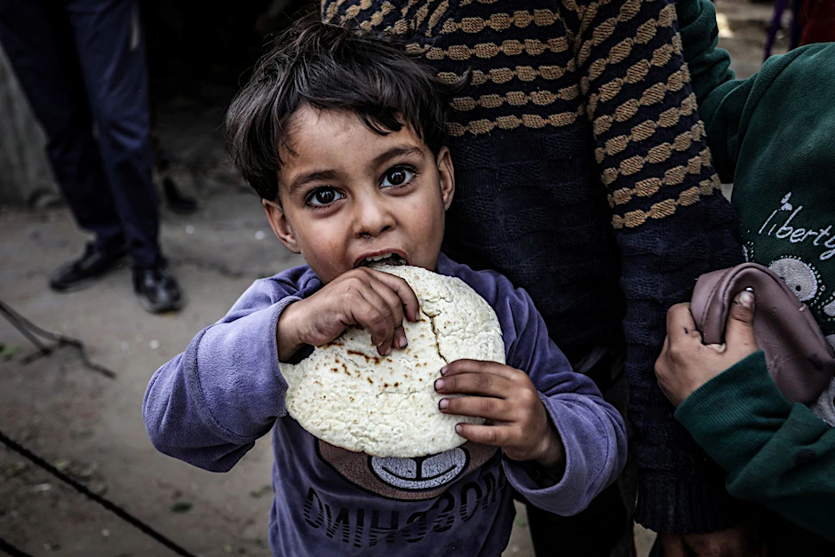 Ein Kind hat ein Fladenbrot erhalten. Im Gazastreifen herrscht Hunger.&nbsp;