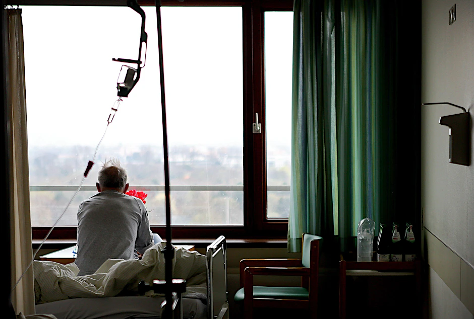 Ein älterer Mann sitzt in einem Krankenhausbett.