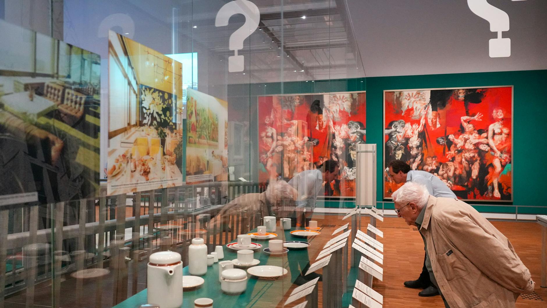 Blick in die Ausstellung „Hin und weg. Der Palast der Republik ist Gegenwart“: In Vitrinen wird das Palast-Geschirr gezeigt. Im Hintergrund hängt das Gemälde „Die rote Fahne – Kampf, Leid und Sieg“ von Willi Sitte. 