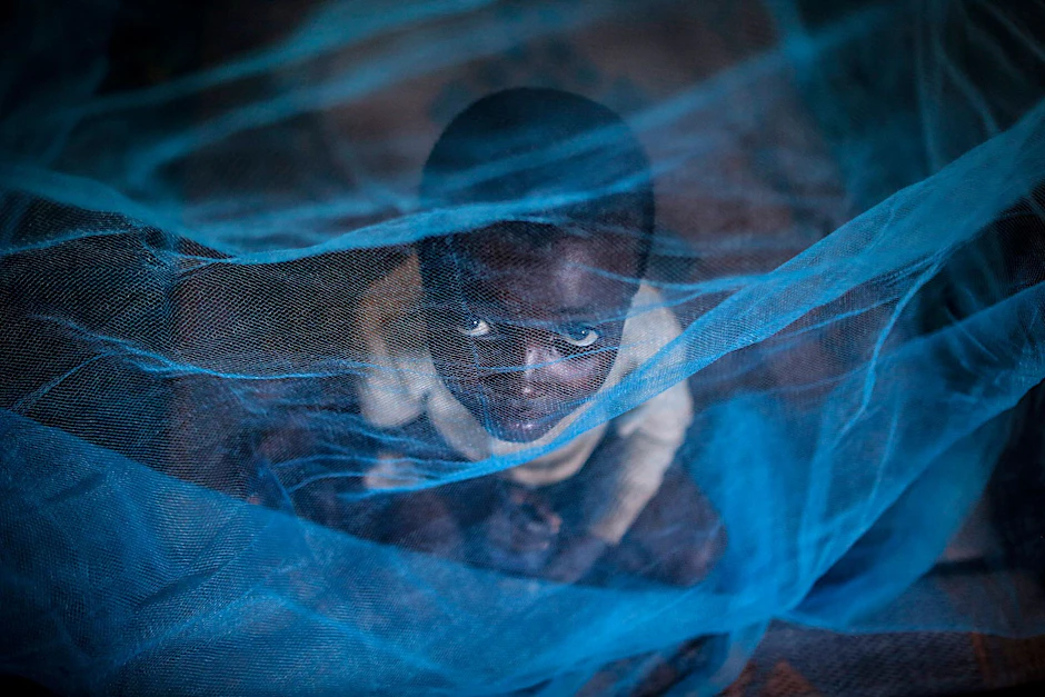 ARCHIV - Ein Flüchtlingskind aus Burundi sitzt in Gashora, Ruanda, unter einem Moskitonetz: Der Malaria-Erreger wird durch Anopheles-Stechmücken übertragen.  