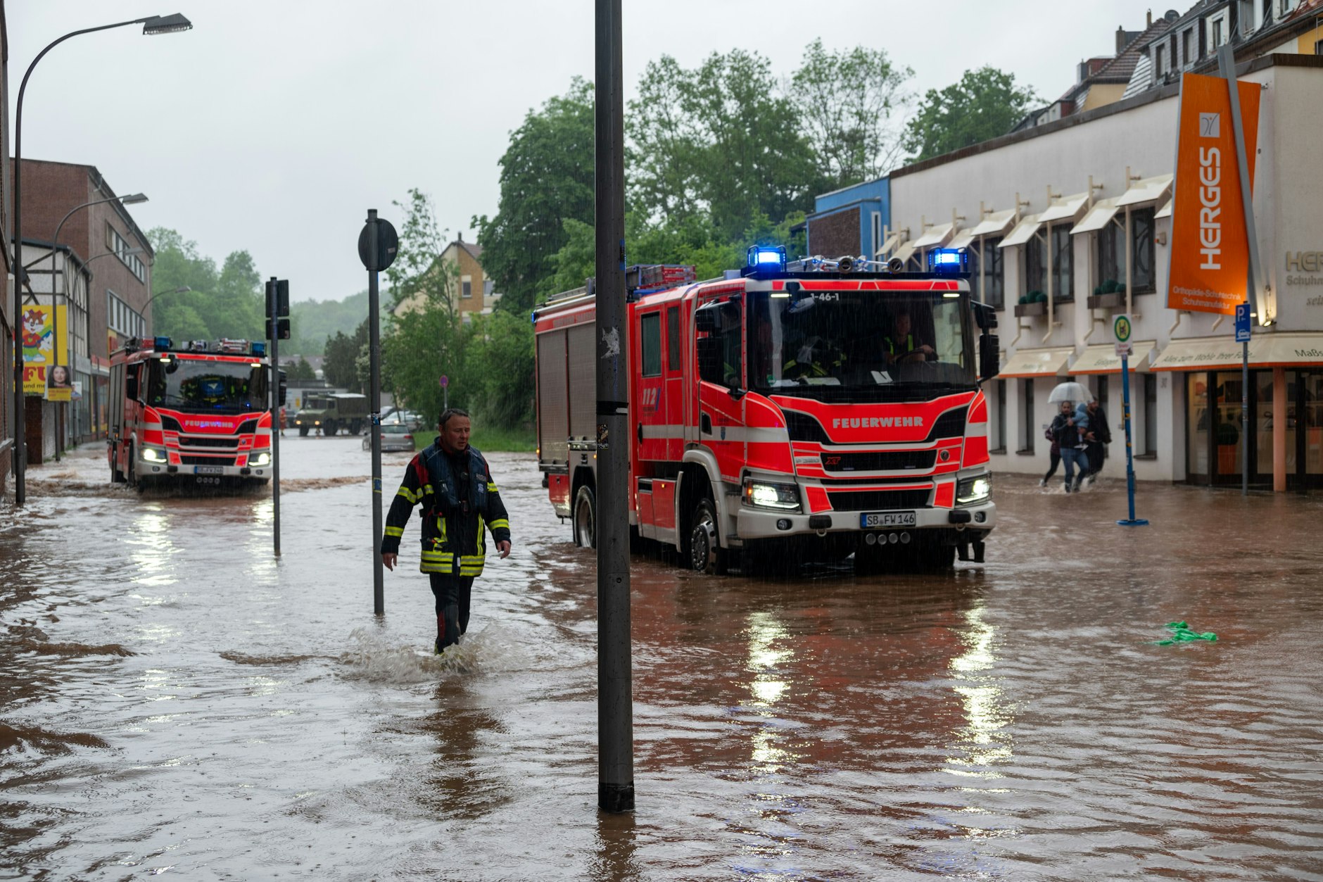 Feuerwehrleute bewegen sich und ihre LKWs durch das Hochwasser in Saarbrücken. 