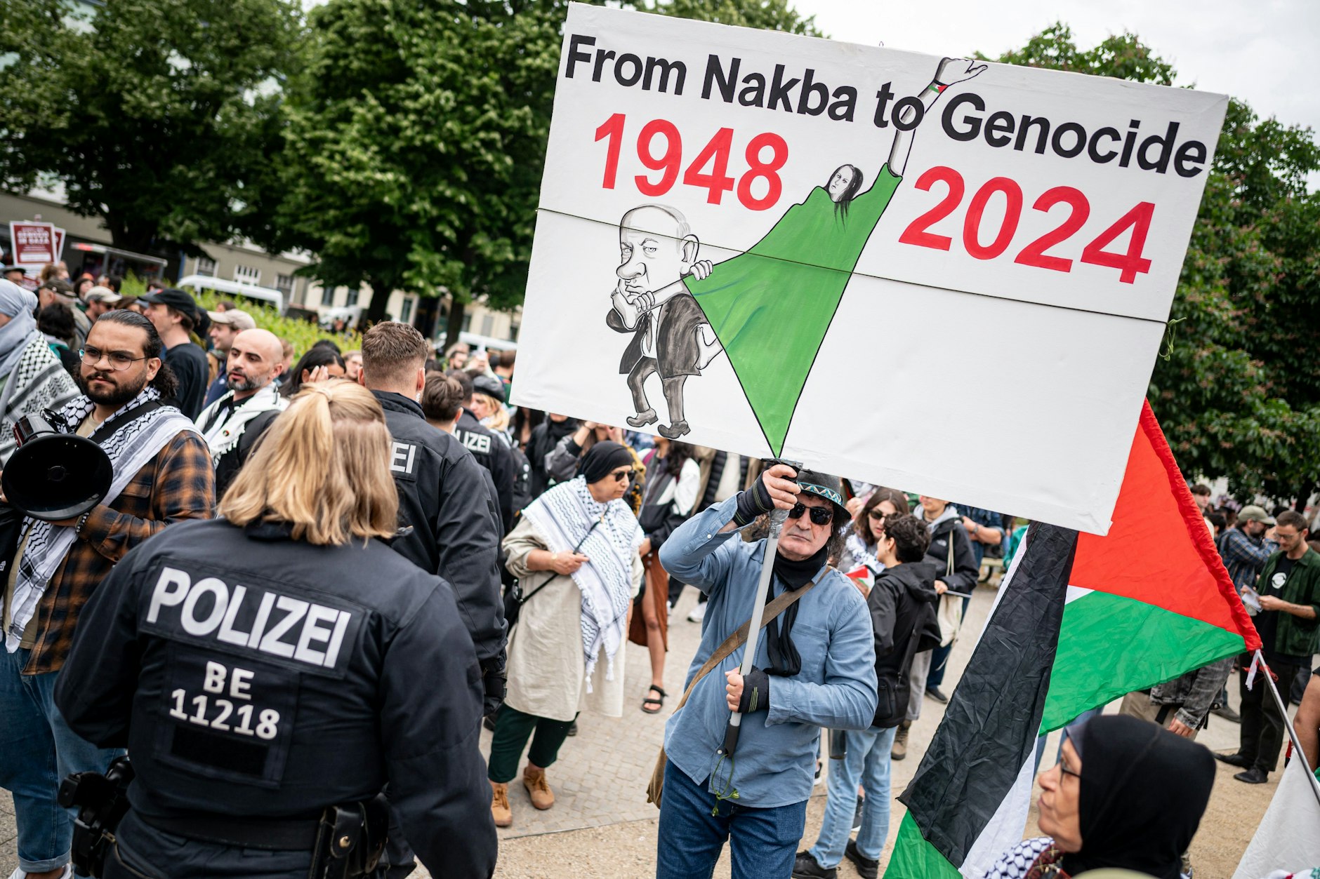 Menschen nehmen an der propalästinensischen Demonstration „Palestine will be free“ teil. „Von Nakba zum Völkermord“ steht auf diesem Plakat.
