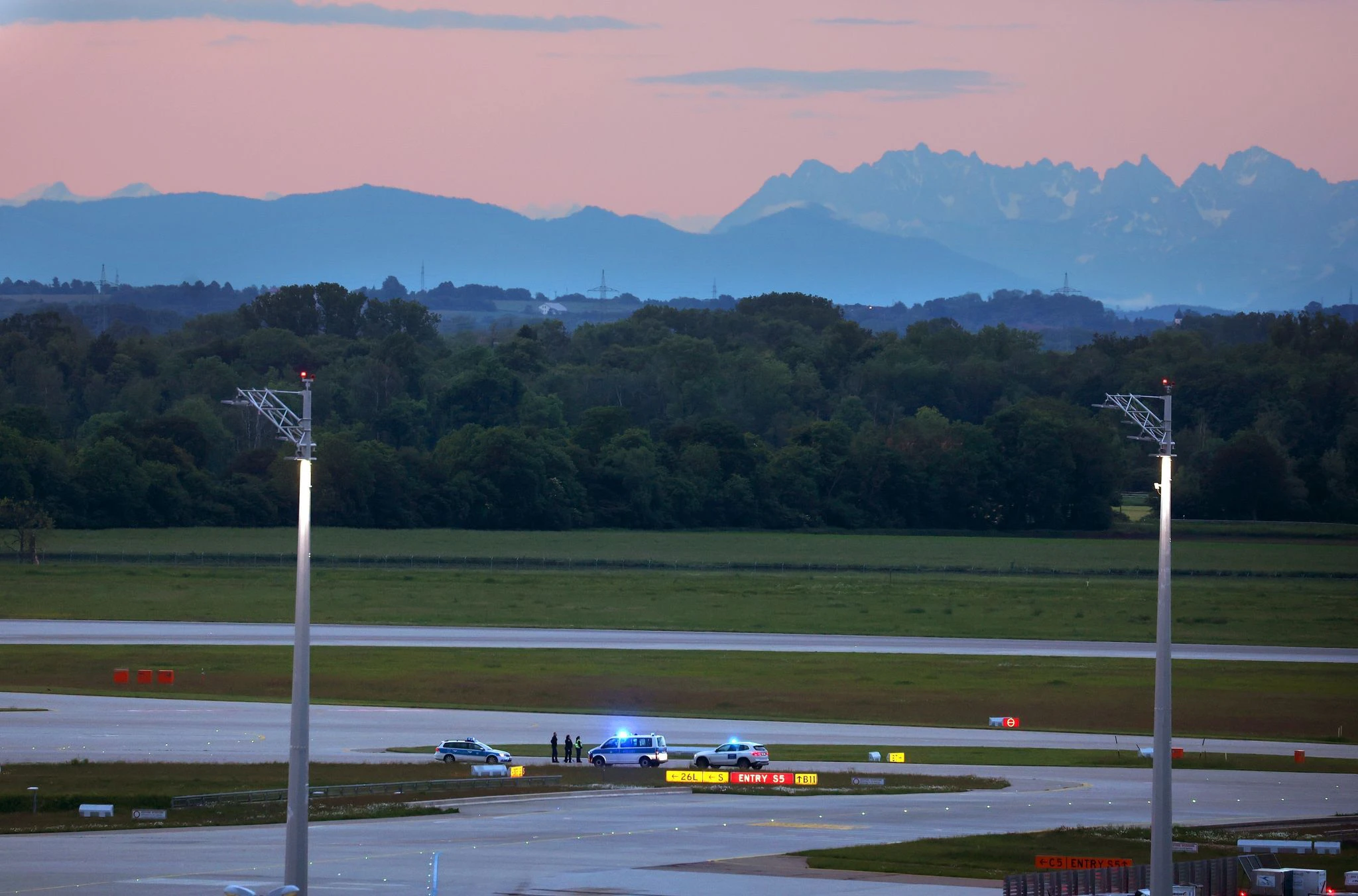 Diesen malerischen Sonnenaufgang vor Bergkulisse dürfen sich einige Menschen heute vielleicht länger als geplant ansehen: Denn Klimaaktivisten haben sich am frühen Morgen auf einer Zufahrt für Start- und Landebahnen am Münchner Flughafen festgeklebt.  