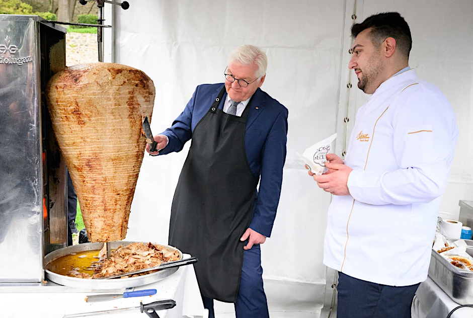 Bundespräsident Frank-Walter Steinmeier schneidet bei einem Empfang in der Sommerresidenz des deutschen Botschafters in Istanbul unter Anleitung des Berliner Gastronomen Arif Keles Dönerfleisch von einem Spieß.