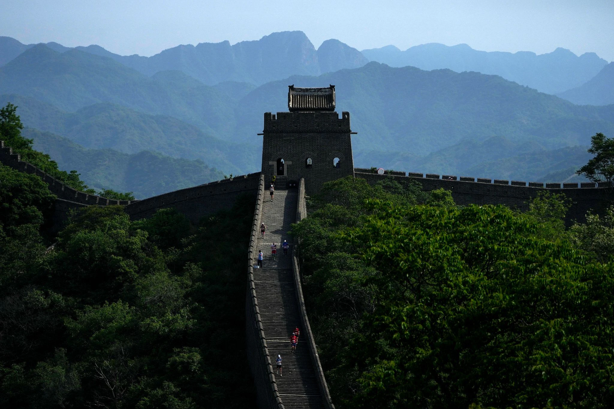 Bei diesem Anblick macht das Schwitzen sicher gleich viel mehr Spaß: Läuferinnen und Läufer bahnen sich ihren Weg auf einem schmalen und steilen Abschnitt entlang der berühmten Chinesischen Mauer. Sie nehmen am Great Wall Marathon teil.  
