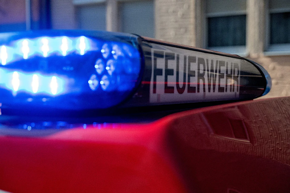 Ein Fahrzeug der Feuerwehr steht mit eingeschaltetem Blaulicht an einem Einsatzort.  