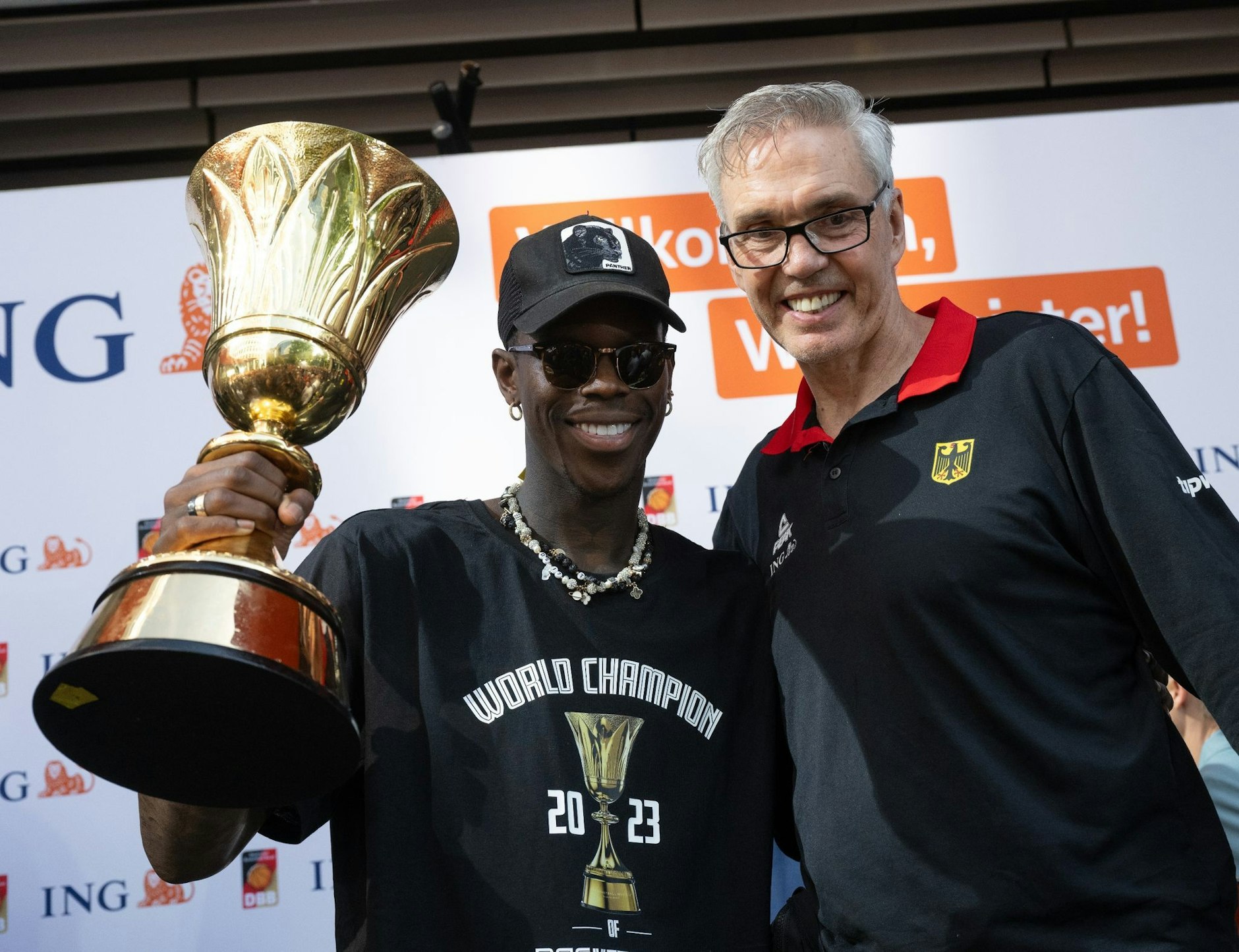 ARCHIV - Dennis Schröder (l) und Basketball-Bundestrainer Gordon Herbert mit dem WM-Pokal.  
