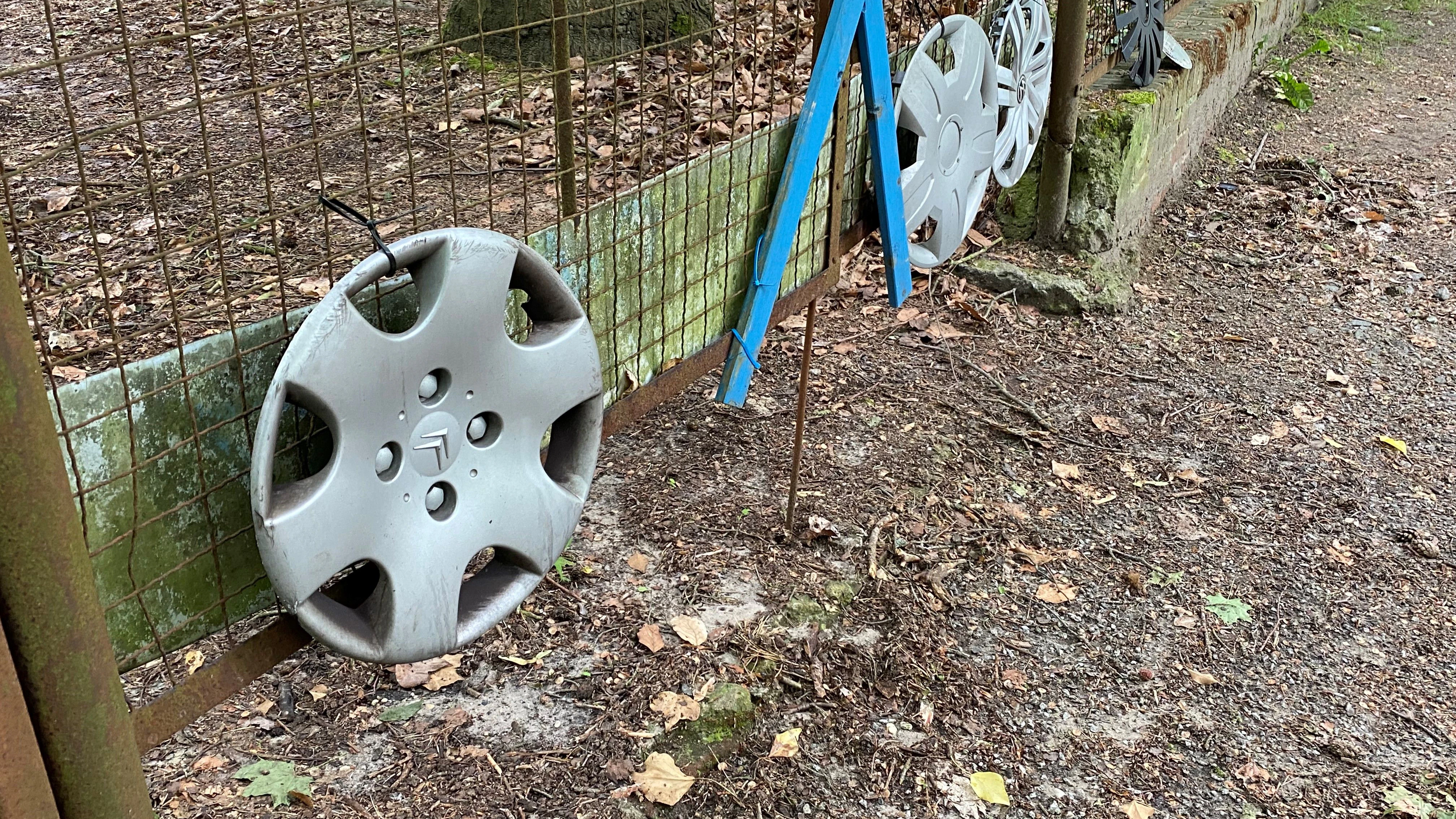 Zum Abholen bereit: In der Rudolf-Breitscheid-Straße stehen Radkappen an einem Zaun, die Autofahrer beim Befahren der Schlaglochpiste verloren haben.