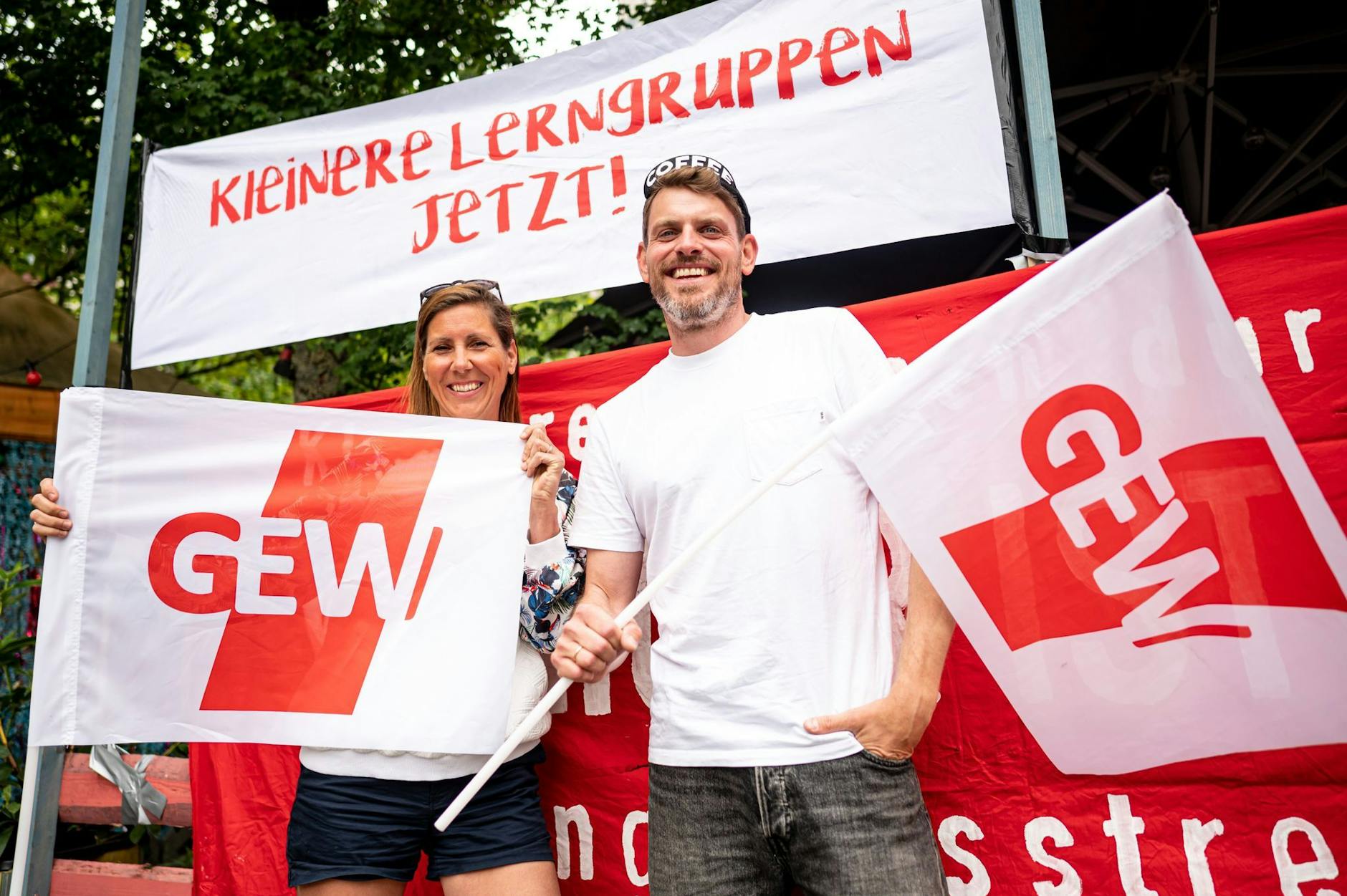 ARCHIV - Sven und Bianca, beide Lehrer an einer Neuköllner Schule, stehen mit zwei GEW-Flaggen beim Warnstreiks an den Berliner Schulen in Berlin-Kreuzberg vor einem Banner mit der Aufschrift "Kleinere Lerngruppen jetzt!".