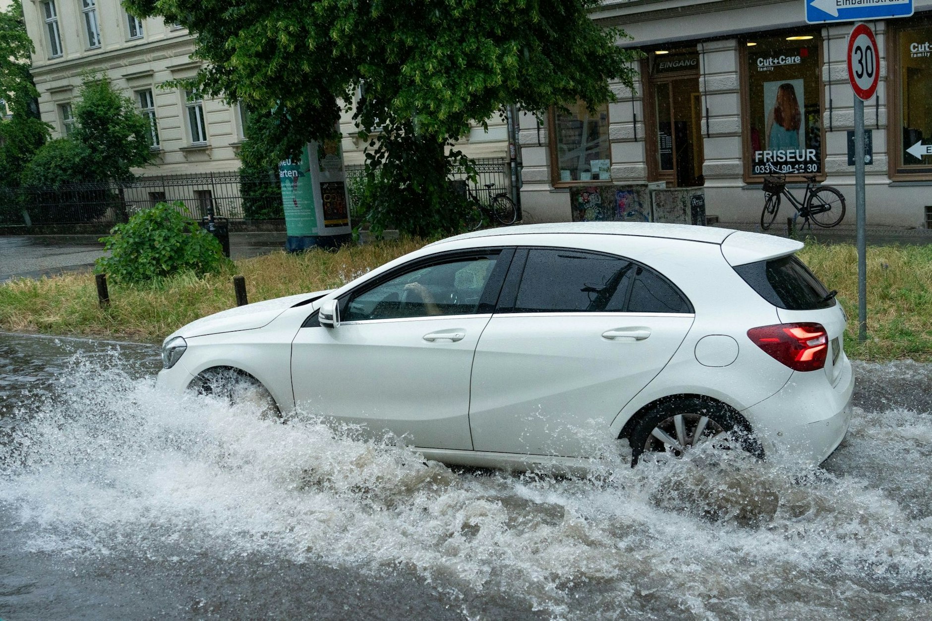 Ein Auto fährt durch der überflutete Geschwister-Scholl-Straße.  