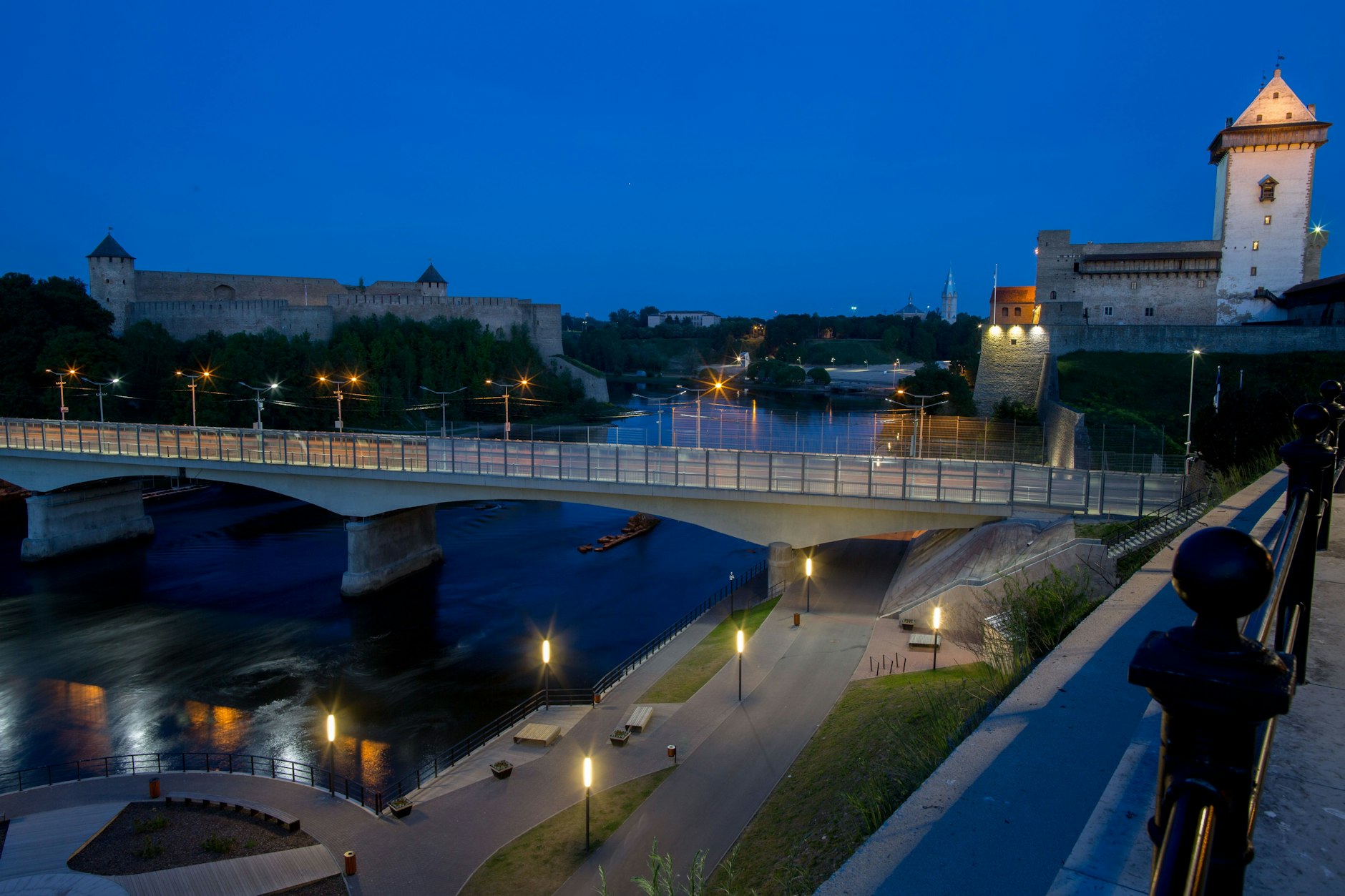 Die mit Zäunen und Kameras gesicherte Grenzbrücke der estnischen Stadt Narva mit der russischen Burg Iwangorod und dem Grenzfluss Narva.