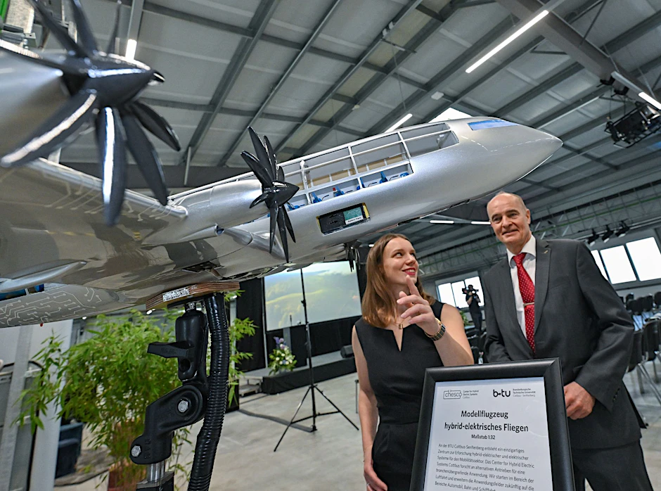 Jane Worlitz (l) und Professor Klaus Höschler stehen in der Forschungsfabrik hinter einem Modell eines hybrid-elektrischen Flugzeuges.  