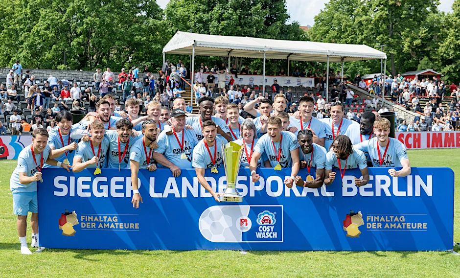 Spieler von Viktoria Berlin feiern mit der Siegertrophäe den Landespokalsieg.  