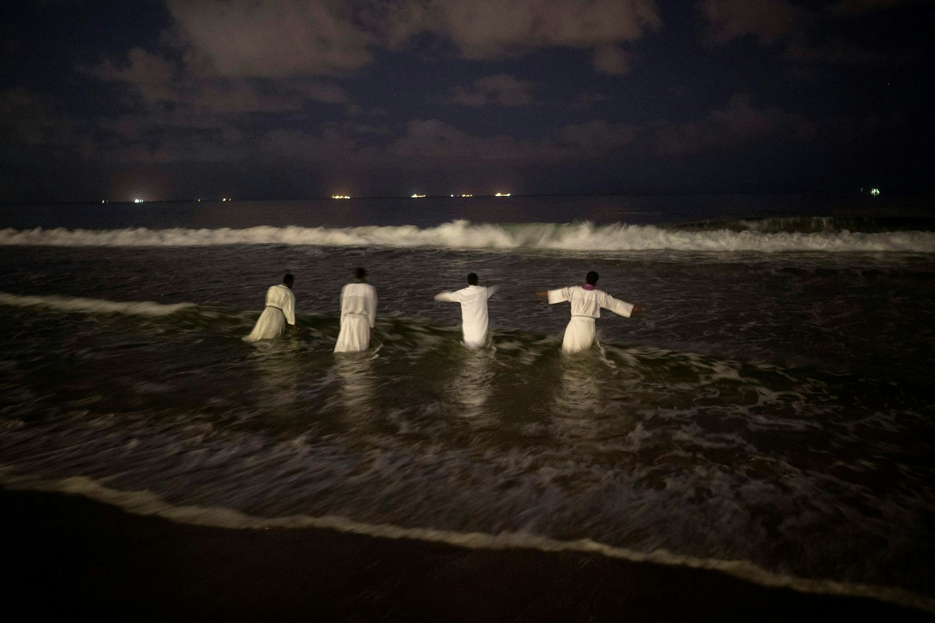 Priester steigen ins Meer, bevor sie die Gläubigen an einem Strand im südafrikanischen Durban taufen.  
