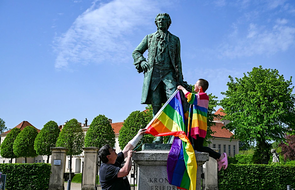 PRODUKTION - Am Denkmal von Kronprinz Friedrich zeigen der Politiker Freke Over und Marie von der Vorbereitungsgruppe des ersten "Christopher Street Day" (CSD) in Rheinsberg die Regenbogenfahne.  