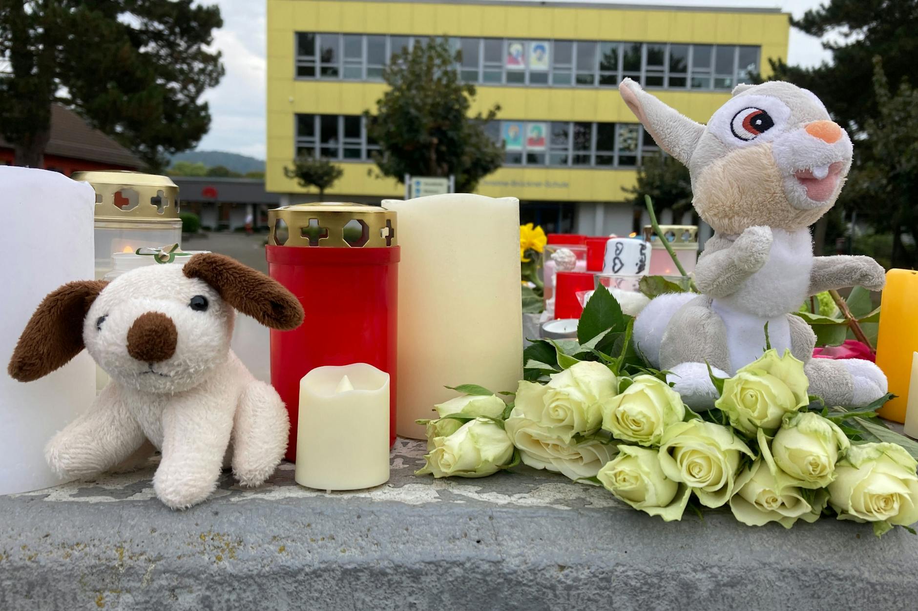 Kerzen, Blumen und Stofftiere stehen vor einer Schule in Bad Emstal (Hessen).
