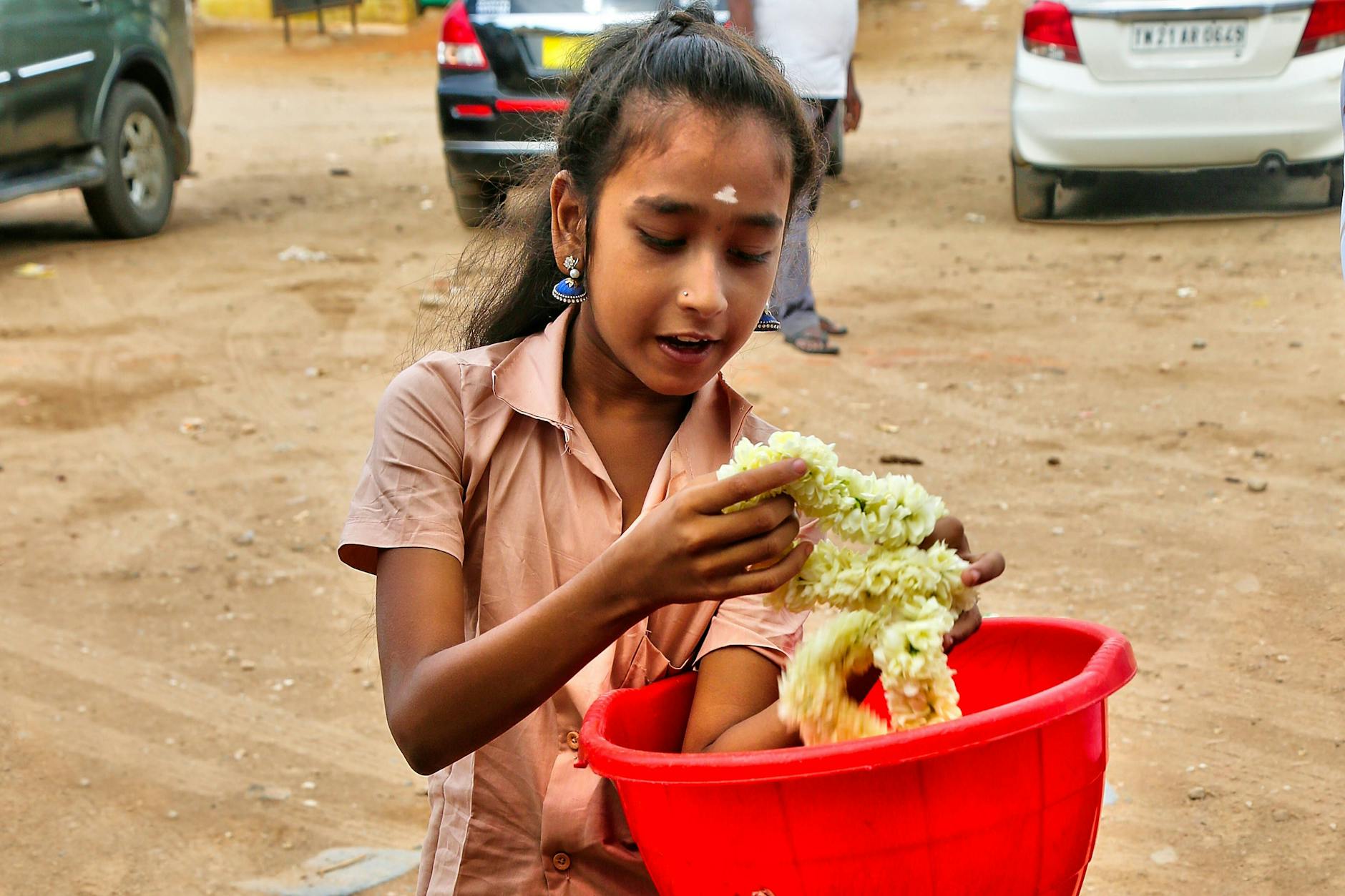 Ein junges Mädchen trägt eine Schale mit Jasminblüten.