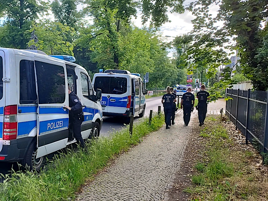 Polizisten gehen am abgesperrten Tatort in der Potsdamer Geschwister-Scholl-Straße entlang.