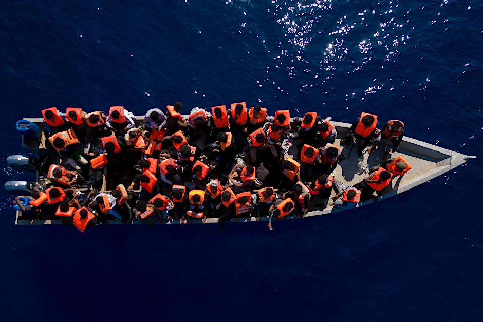 Aus Eritrea, Libyen und dem Sudan geflüchtete Menschen sitzen in einem Holzboot im Mittelmeer, etwa 30 Meilen nördlich von Libyen.