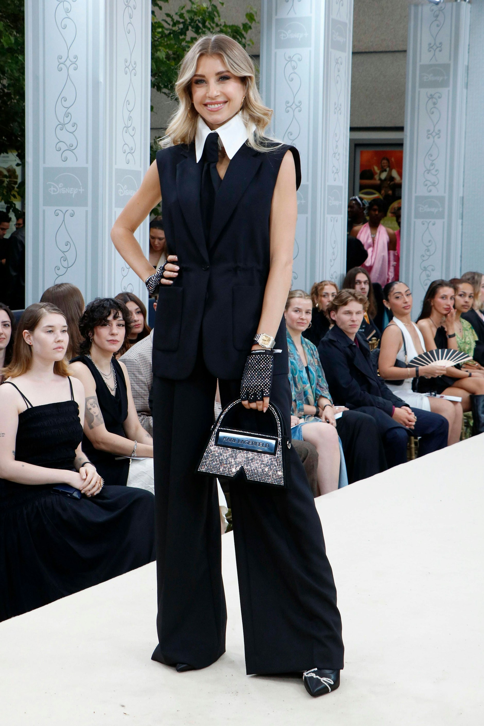 <strong>FLOP:</strong> Als sie die Einladung zur Premiere von „Becoming Karl Lagerfeld“ bekam, habe sie nicht gezögert, schließlich sei sie ein Riesen-Fan des 2019 verstorbenen Modedesigners. Das ließ <strong>Cathy Hummels</strong> ihre Instagram-Follower wissen, bevor sie die Reise nach Berlin antrat. Um ihre Ehrerbietung deutlich zu machen, warf sich <a href="https://www.berliner-zeitung.de/topics/cathy-hummels">Hummels</a> in eine Art Allover-Lagerfeld-Montur. Nicht nur hatten die Haare einen leichten Grauschleier, auch das schwarze Outfit mit weiter Hose, ärmellosem Hemd und Krawatte deuteten auf den Altmeister hin. Hummels ließ sich von der Marke Karl Lagerfeld ausstatten, trug fingerlose Handschuhe und Krawatte, dazu weißen Kragen, ganz wie ihr Idol. Aber es lässt sich trotz aller Mühen nicht verhehlen: Wir sehen hier eben nicht Karl Lagerfeld, sondern Cathy Hummels. Und denken bei diesem Look eher an Charlie Chaplin, den freundlichen Oberkellner oder einen Pinguin.