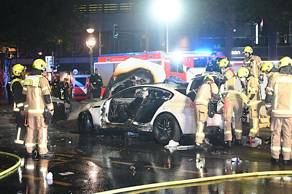Feuerwehrleute kümmern sich um die Verletzten und das Autowrack auf der Berliner Tauentzienstraße.
