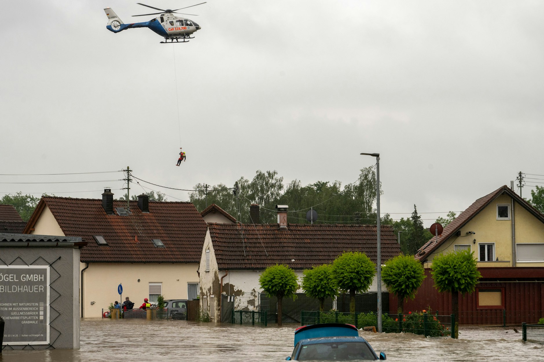 Aus einem Polizeihubschrauber in Babenhausen (Bayern) wird ein Wasserretter abgeseilt. 