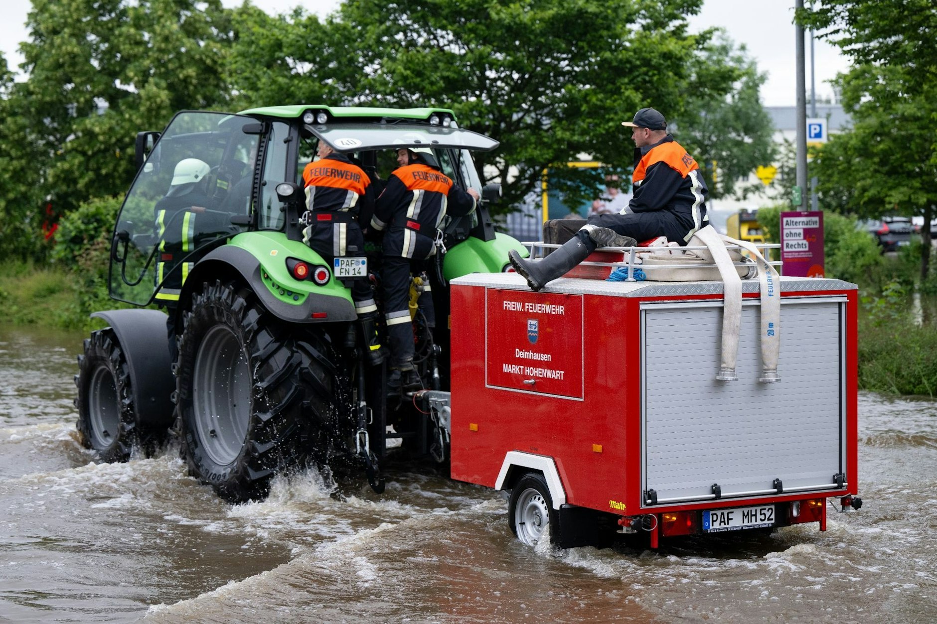 Feuerwehrleute fahren in Reichertshofen über eine überflutete Straße.