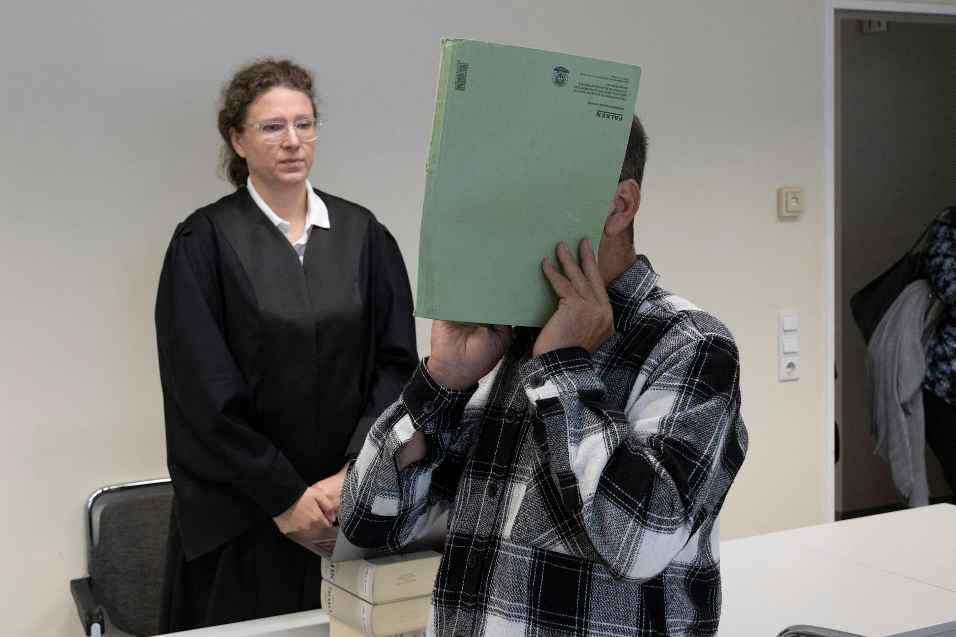 Der Angeklagte steht neben seiner Anwältin im Gerichtssaal.