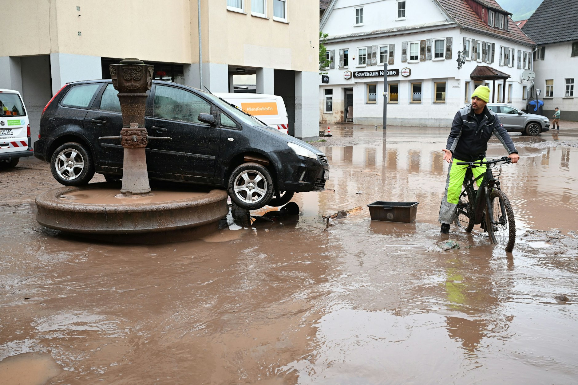 Auf einem Brunnen in Rudersberg steht ein durch ein Hochwasser weggespültes Auto.